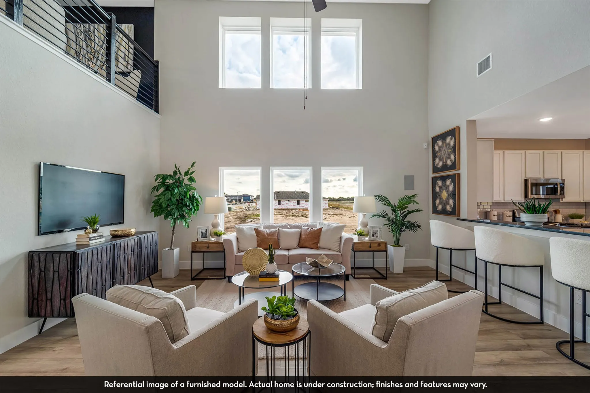 Two-story living area with high ceilings, multiple large windows, and wood-finish flooring