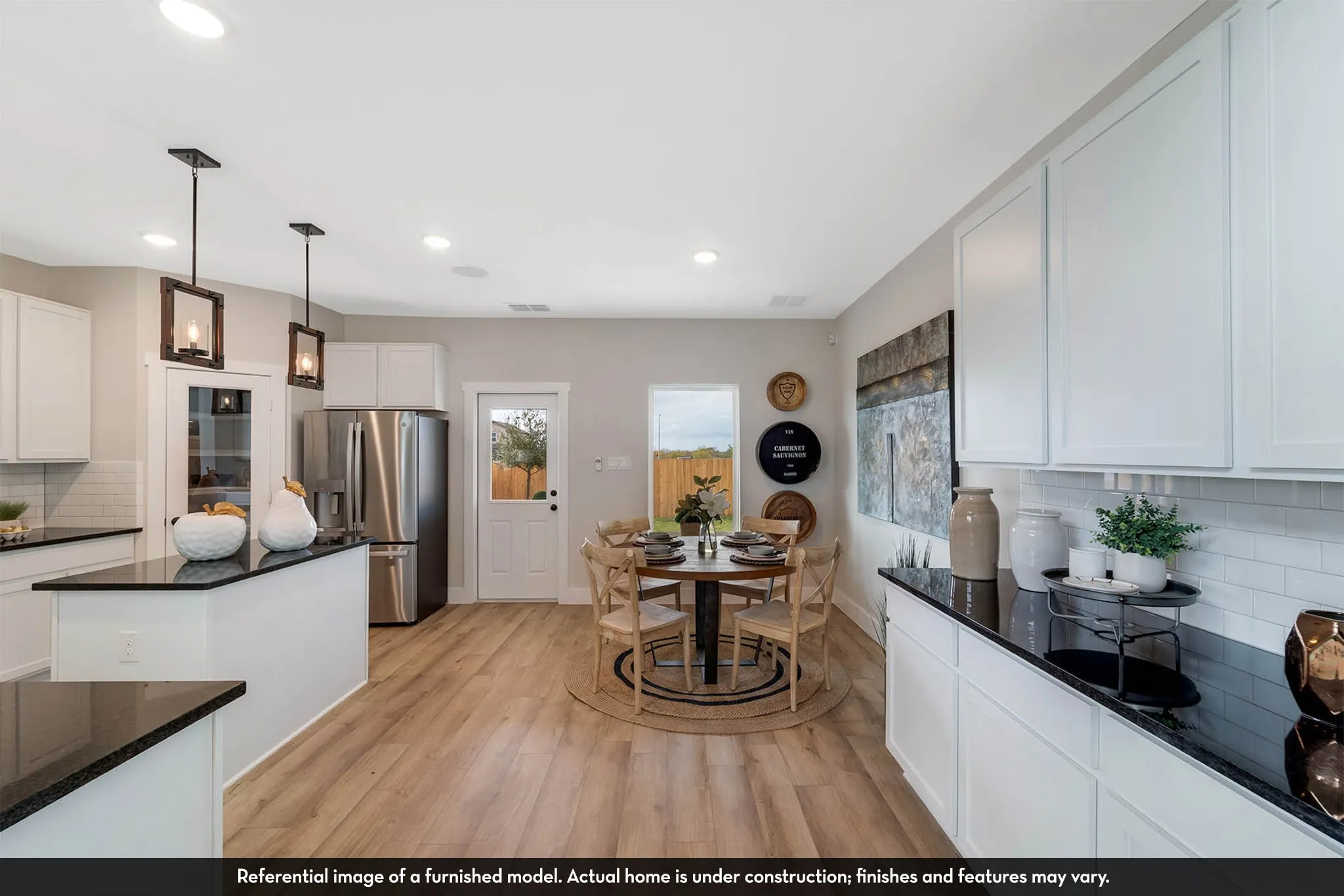 White cabinetry, dark countertops, wood-finish flooring, recessed lighting, and stainless steel appliances