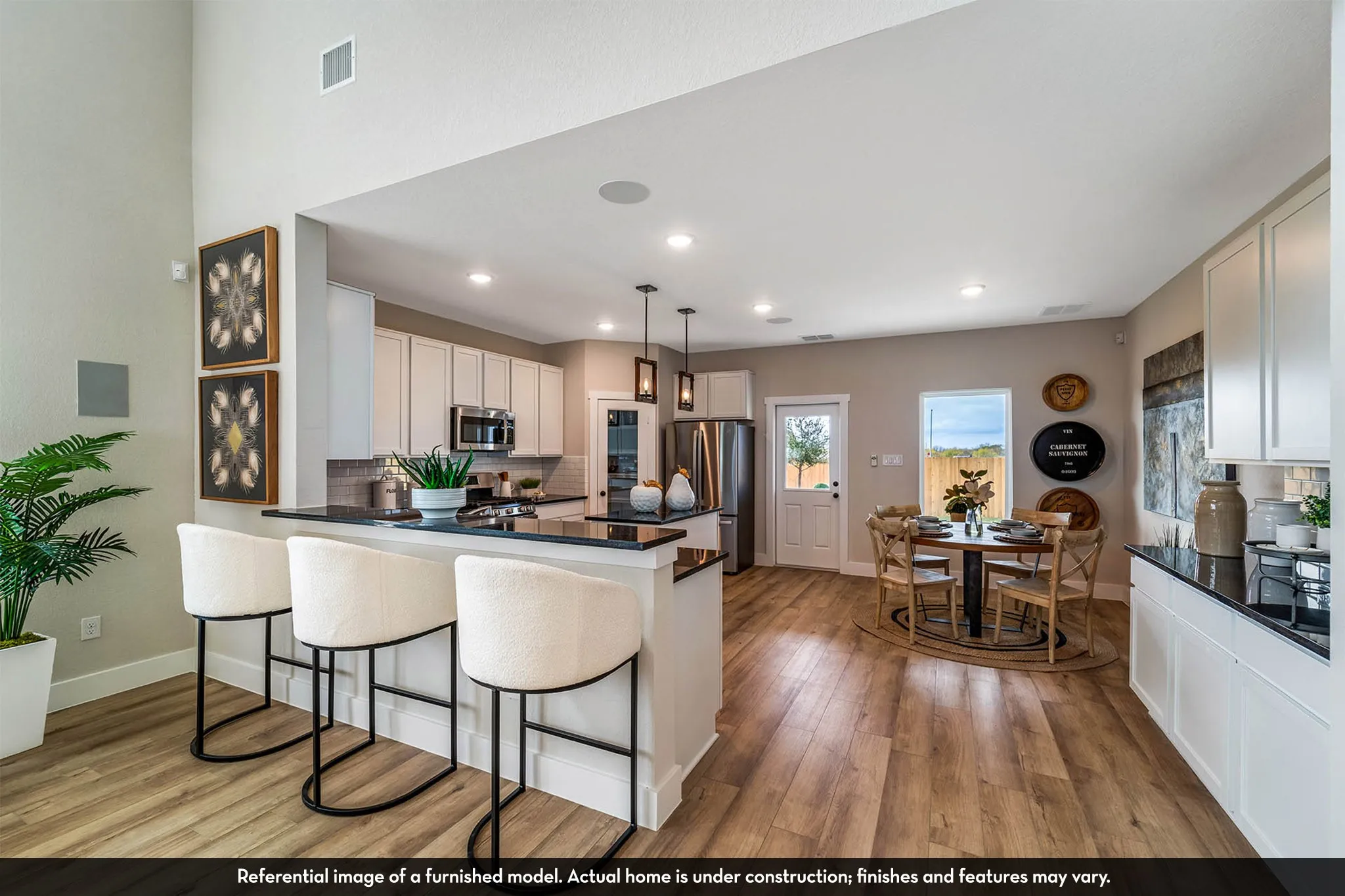 Kitchen and dining area featuring wood-finish flooring, white cabinetry, dark countertops, and stainless steel appliances