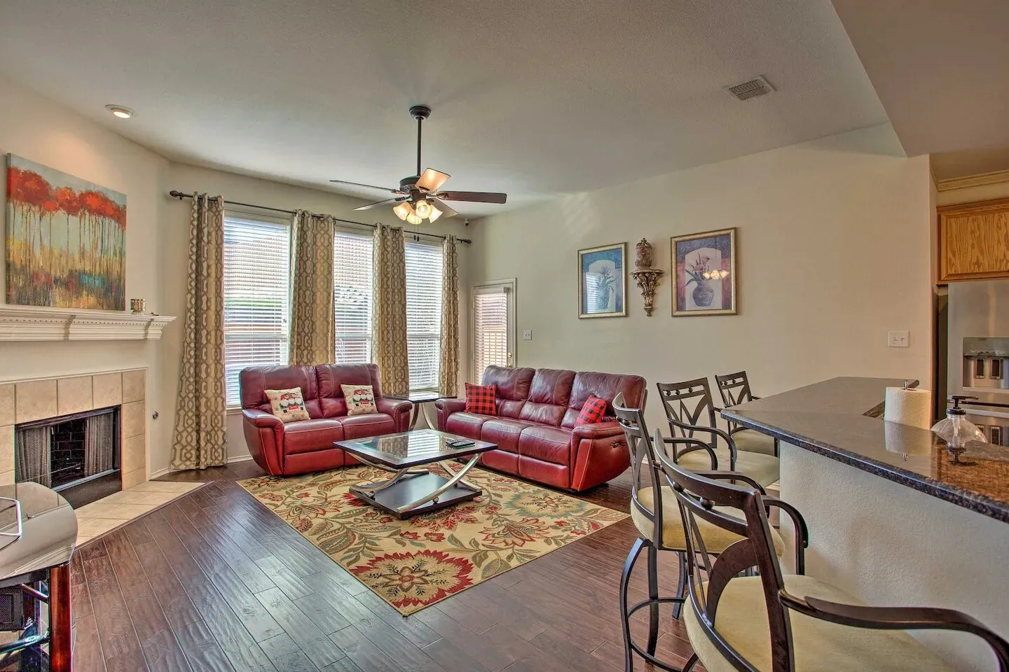 Open-concept living space featuring wood-finish flooring, a tiled fireplace with a mantel, and multiple windows