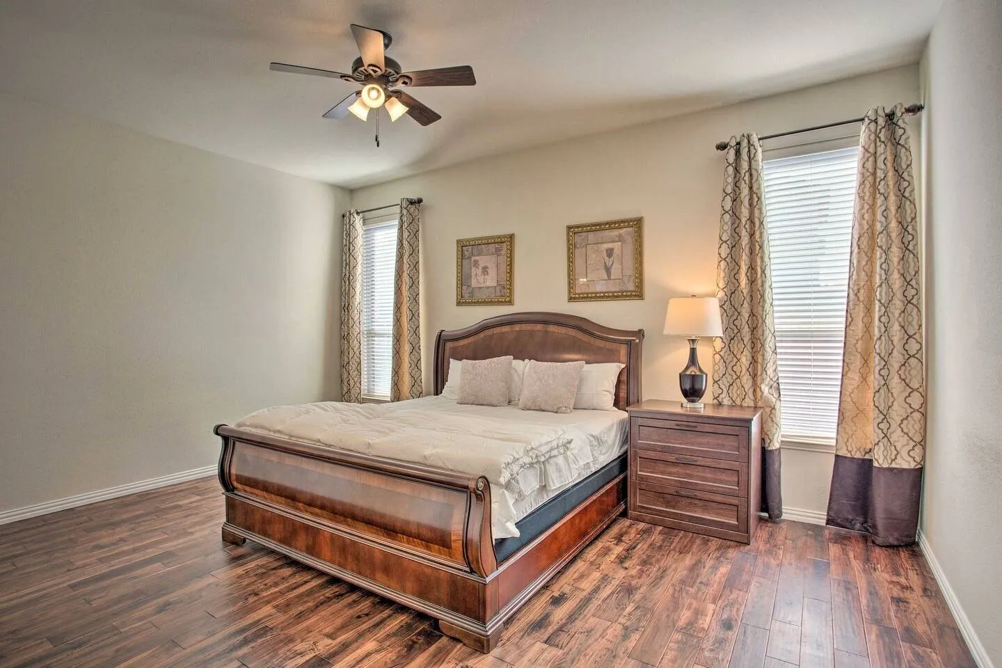 Wood-finish flooring, ceiling fan with integrated lighting, and two windows with blinds
