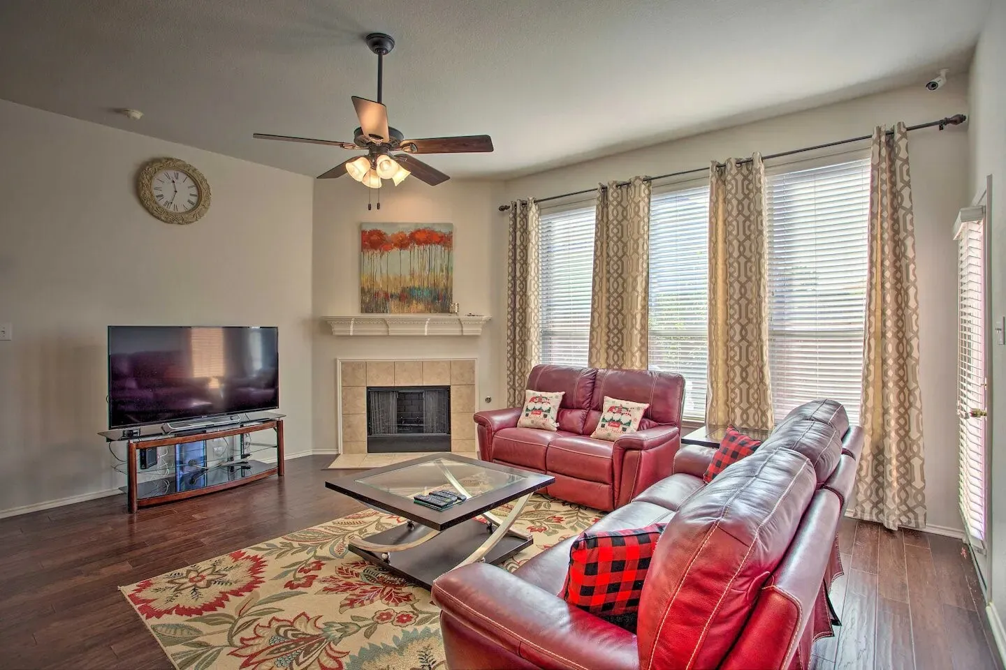Wood-finish flooring throughout, multiple windows with blinds, built-in fireplace with tile surround, ceiling fan with integrated lighting