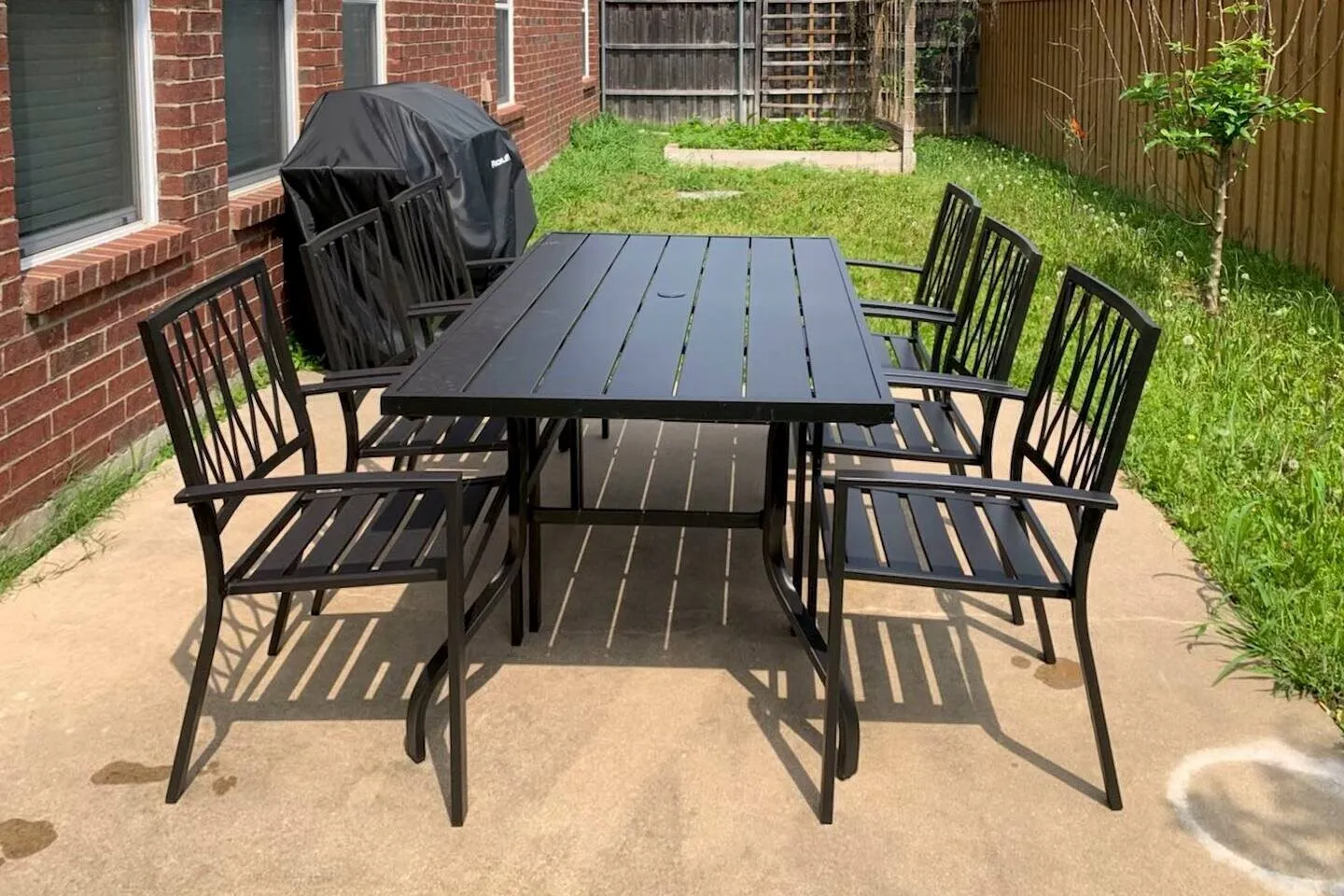 Concrete patio area with a brick exterior and a privacy fence
