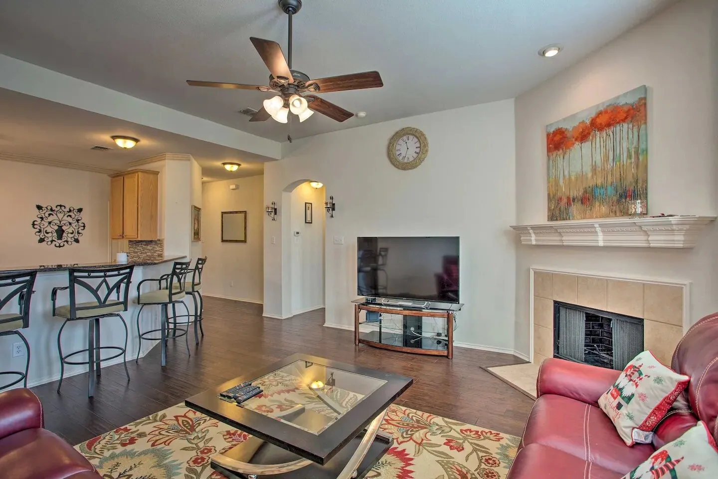 Living area featuring wood-finish flooring, a ceiling fan, and a fireplace with a tile surround and decorative mantel