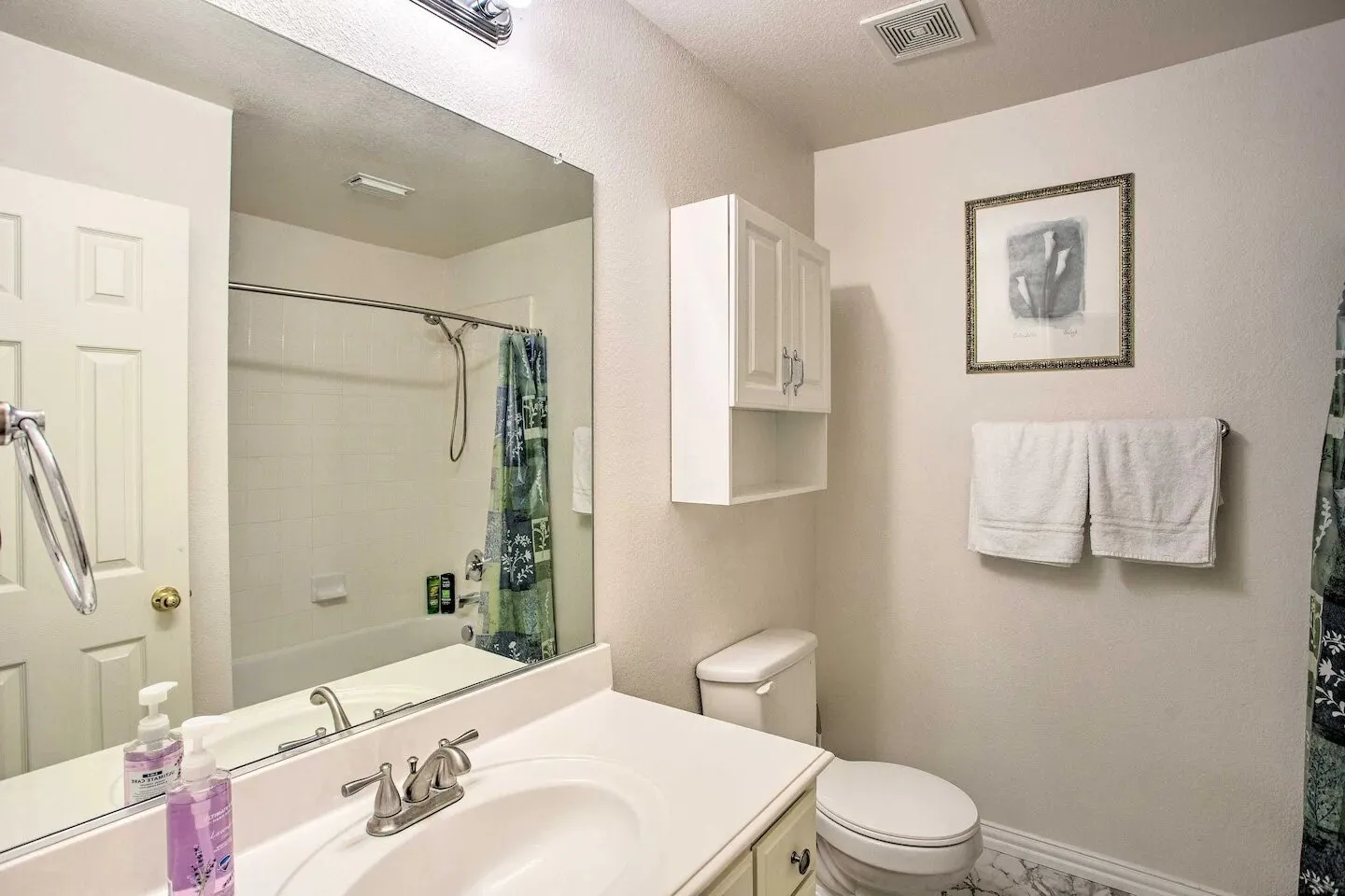 White vanity with an integrated sink, brushed nickel faucet, and extensive mirror