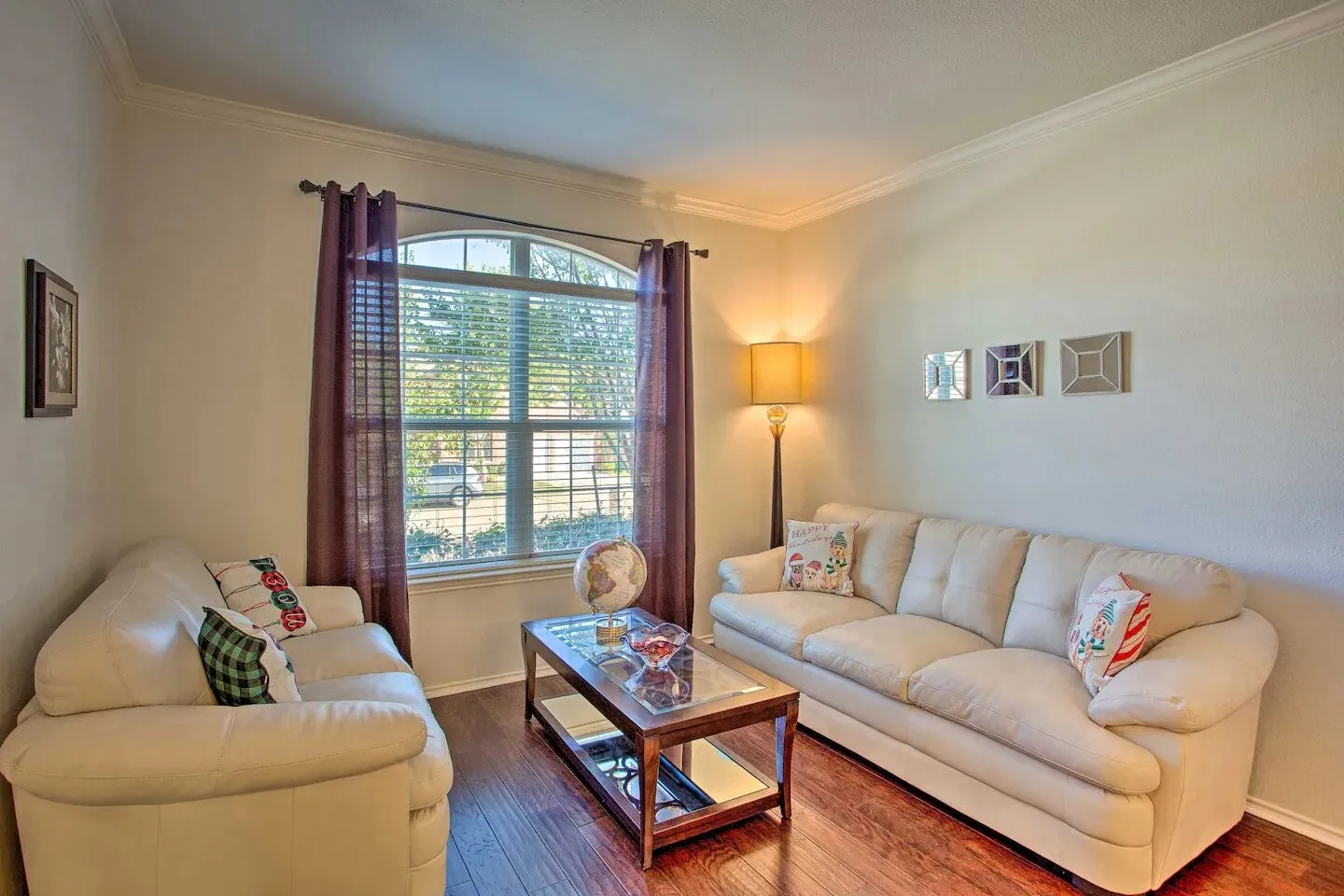 Wood-finish flooring, crown molding, and an arched window provide architectural detail in this living space