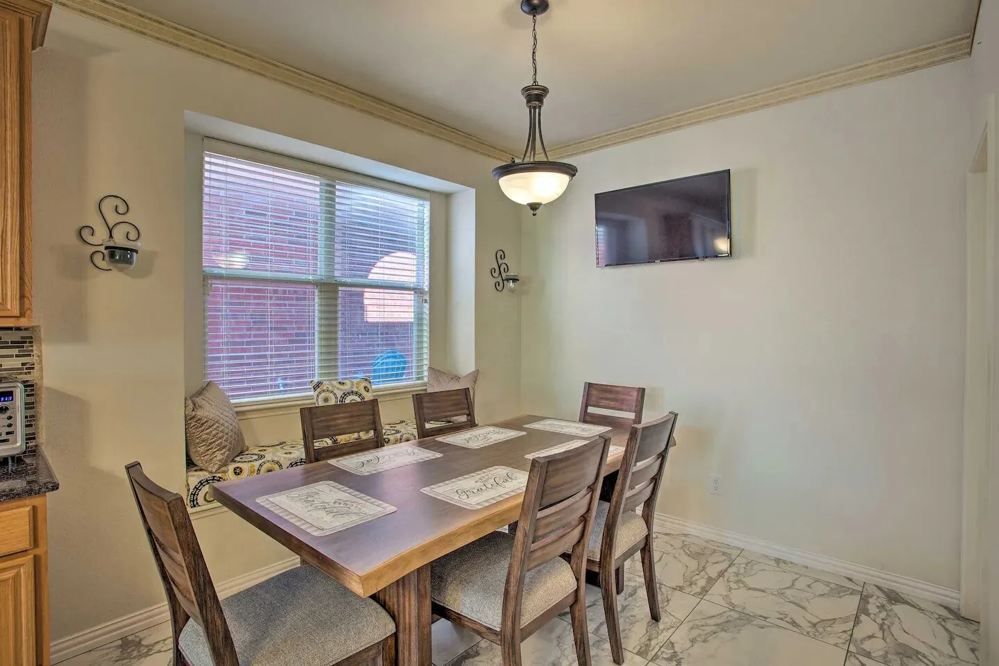 Dining space featuring a built-in window bench, crown molding, and a decorative pendant light fixture