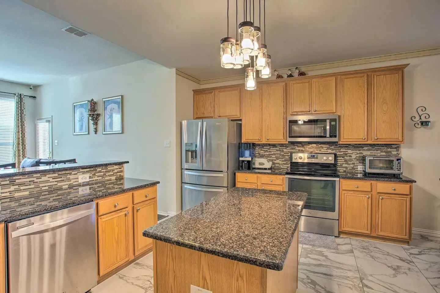 Kitchen featuring a central island, wood cabinetry, stone countertops, and stainless steel appliances