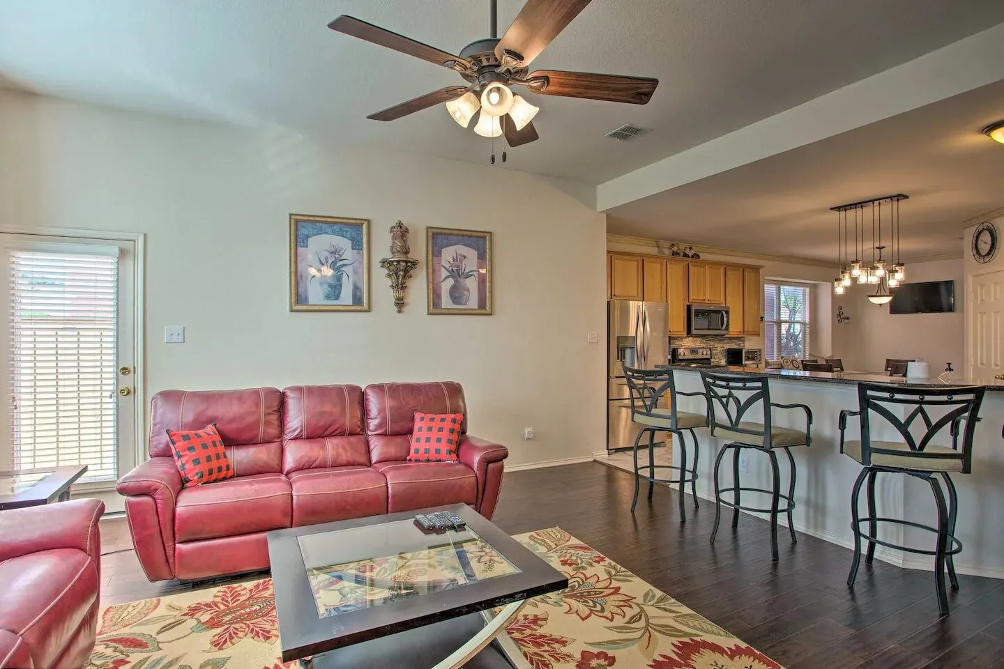 Vaulted ceiling with a ceiling fan, dark wood-finish flooring, and a breakfast bar with pendant lighting