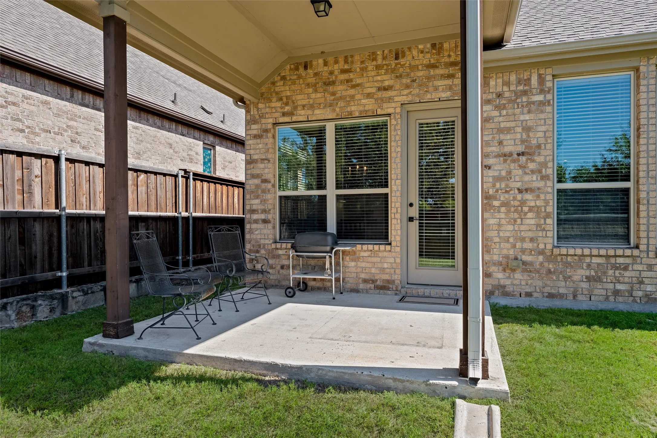 Covered patio with a concrete slab, brick exterior, and a privacy fence