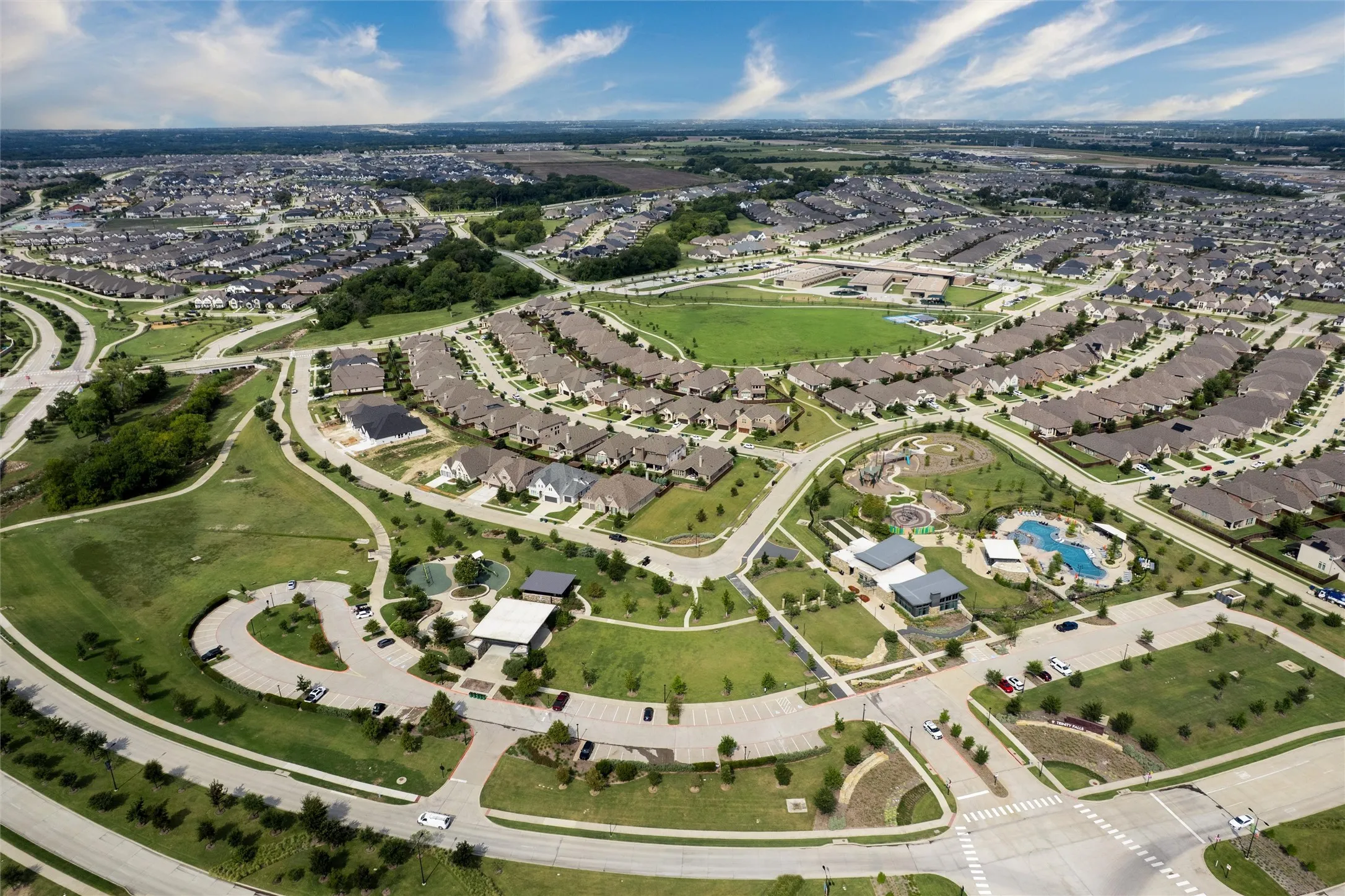 Sprawling community with extensive green spaces, a large recreational pool, multiple playgrounds, and paved walking paths