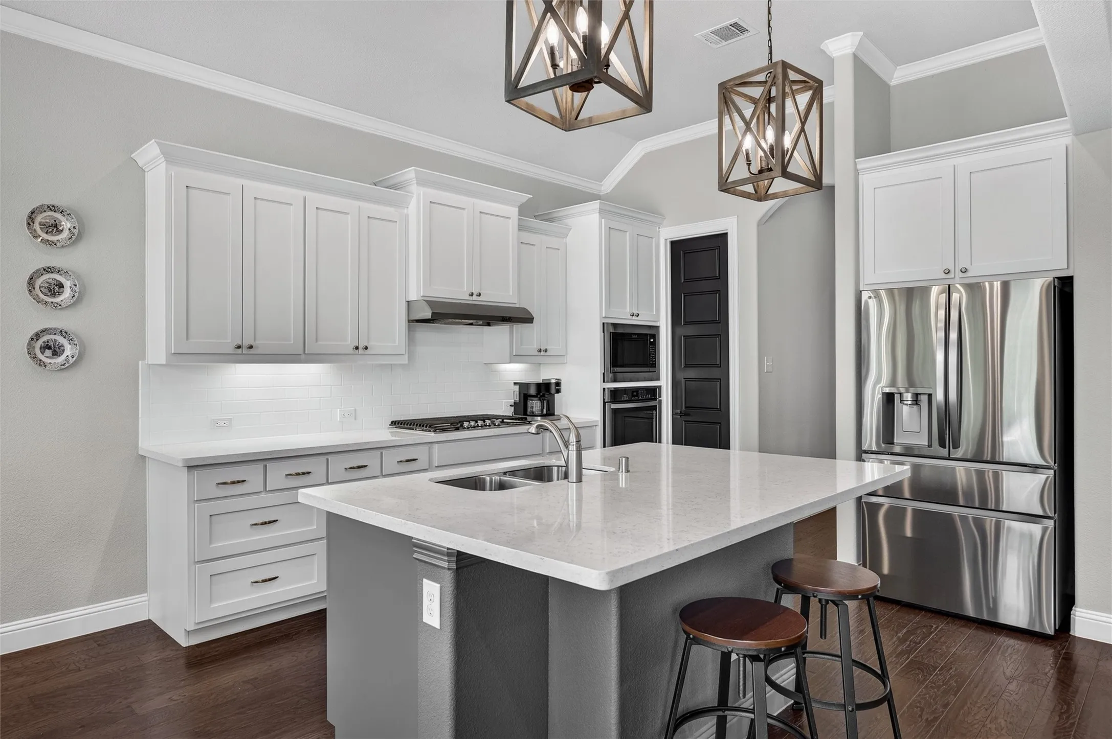 Kitchen featuring white shaker cabinetry, stainless steel appliances, a center island with countertop seating, a subway tile backsplash, and wood-finish flooring