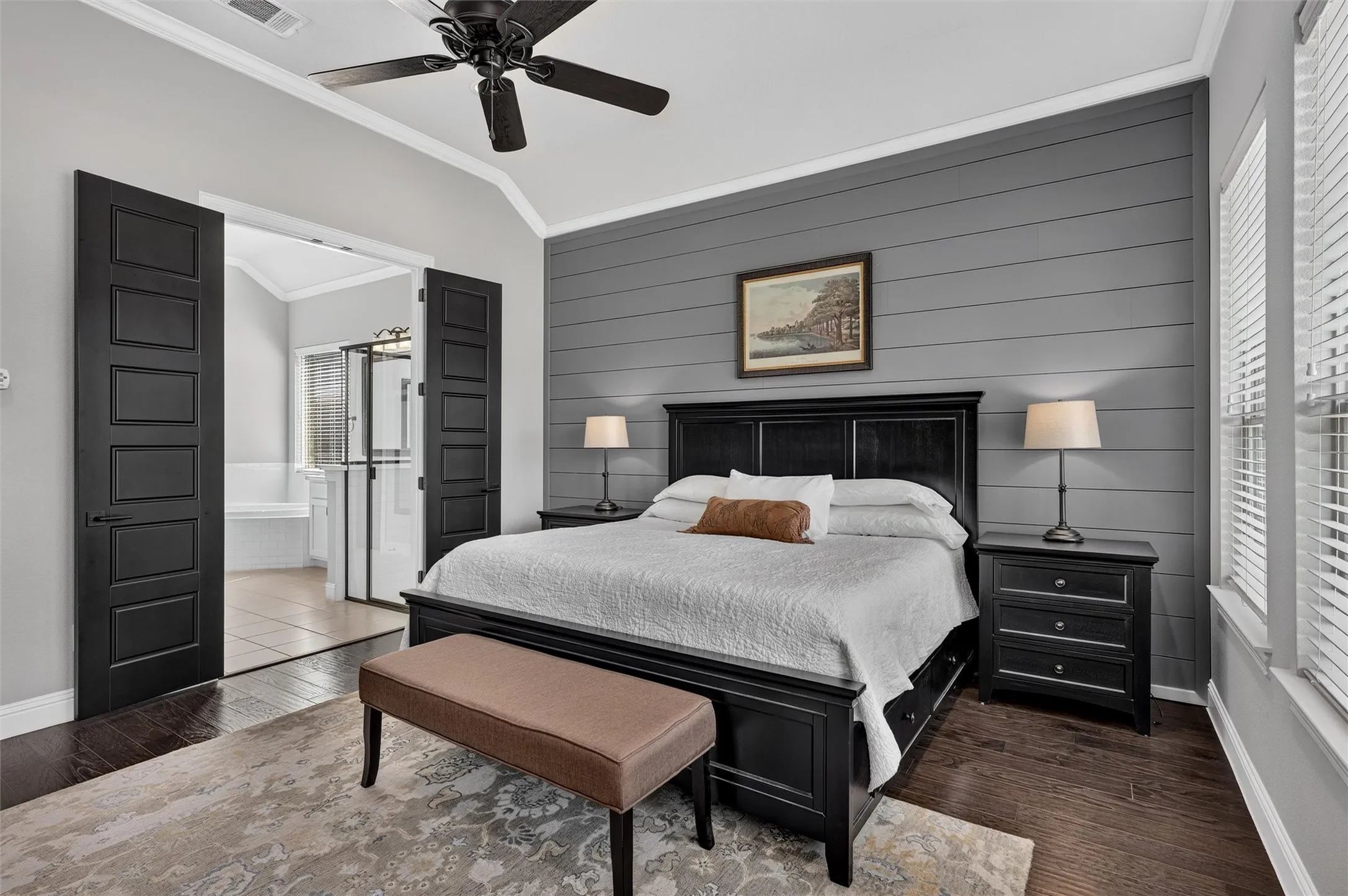Vaulted ceiling with a ceiling fan, dark wood-finish flooring, accent wall with horizontal paneling, double doors, and a window with blinds