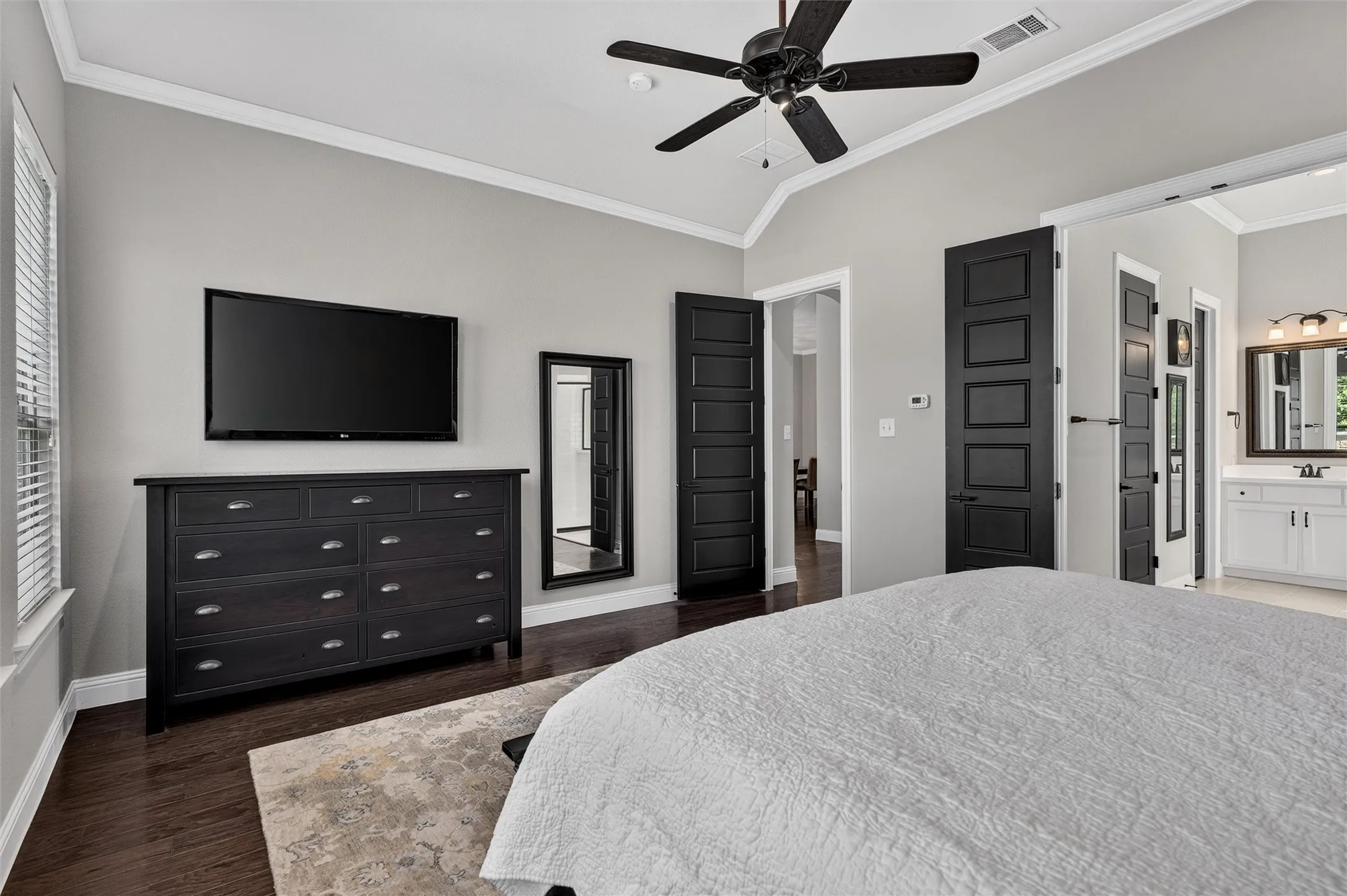 Vaulted ceiling featuring a ceiling fan, dark wood-finish flooring, and crown molding