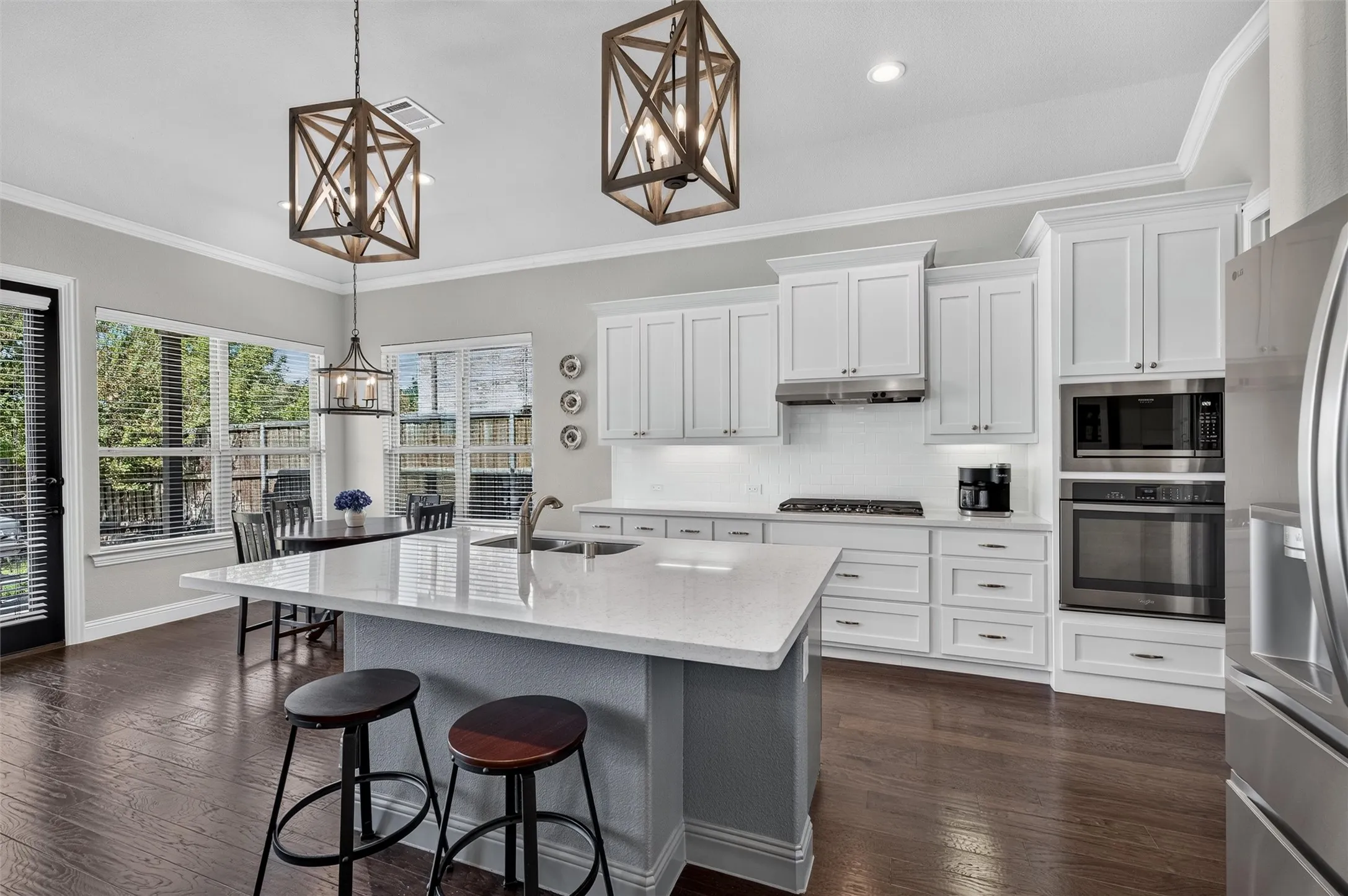 Kitchen featuring a white quartz-finish island, dark wood-finish flooring, white cabinetry, stainless steel appliances, and multiple windows