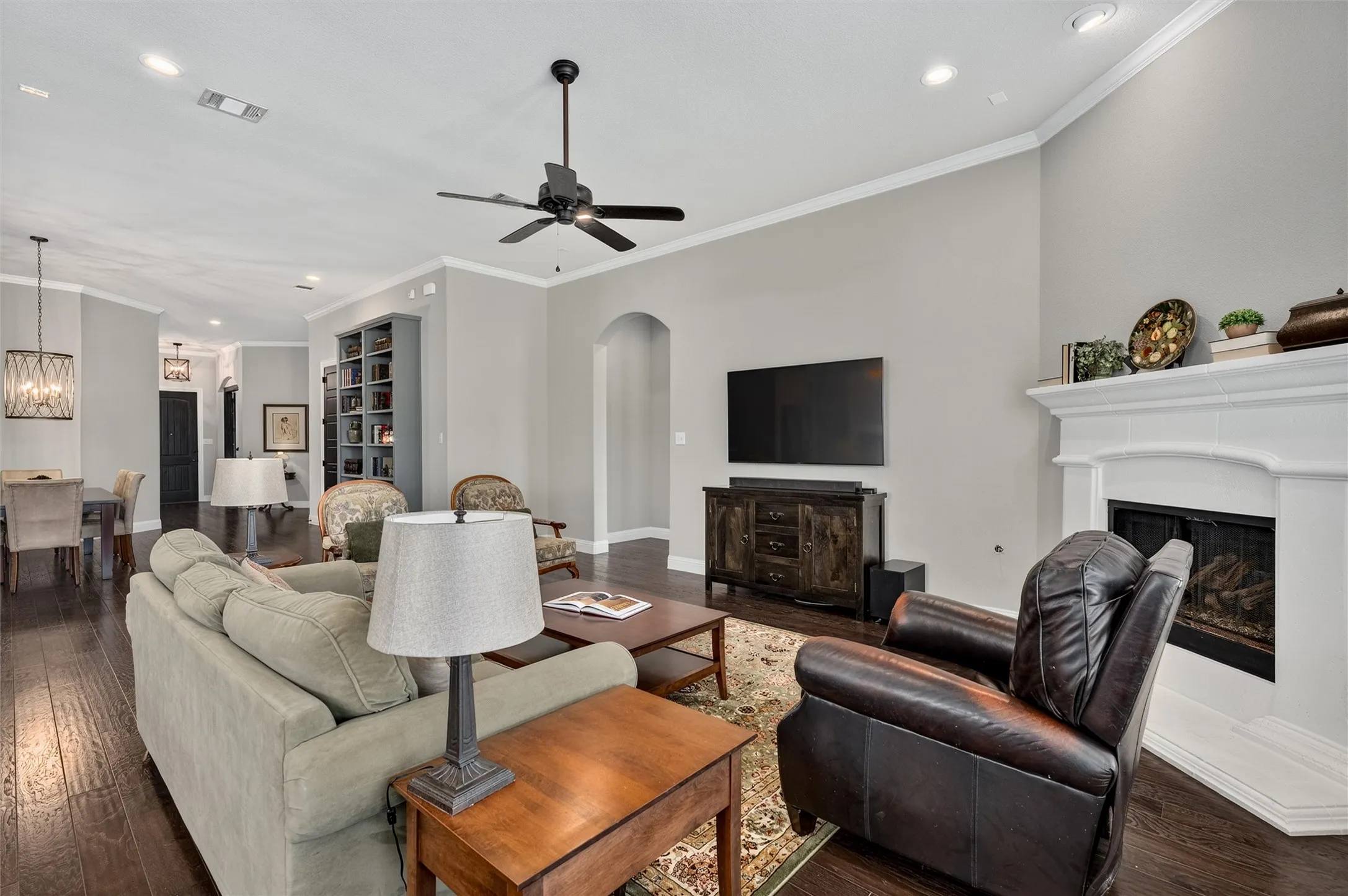 Hardwood flooring throughout, recessed lighting, crown molding, a built-in fireplace, and an arched entry