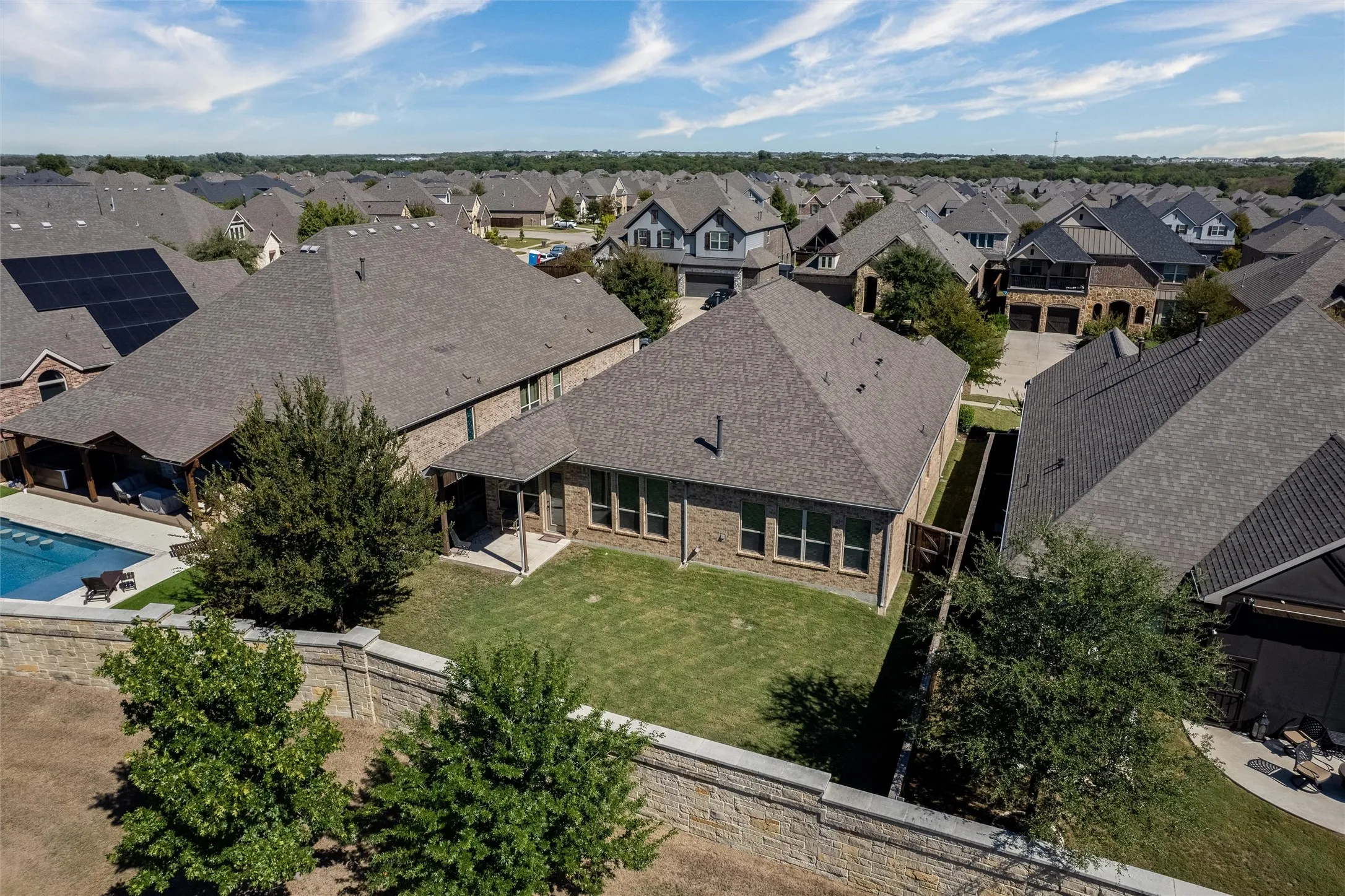 Expansive backyard featuring a manicured lawn, a swimming pool, and a covered patio area