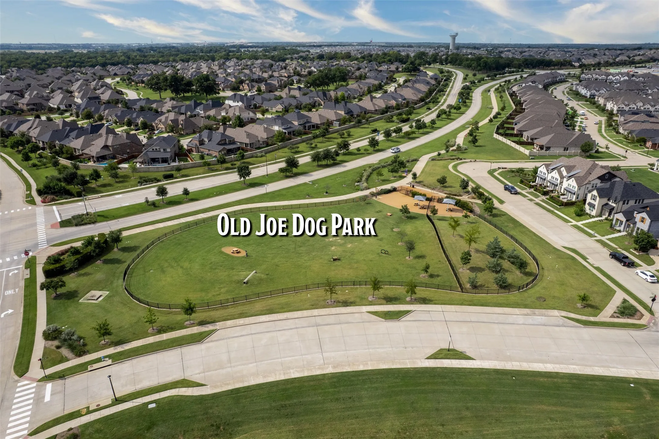 Community park with a fenced dog park area, surrounded by residential streets and landscaped green spaces