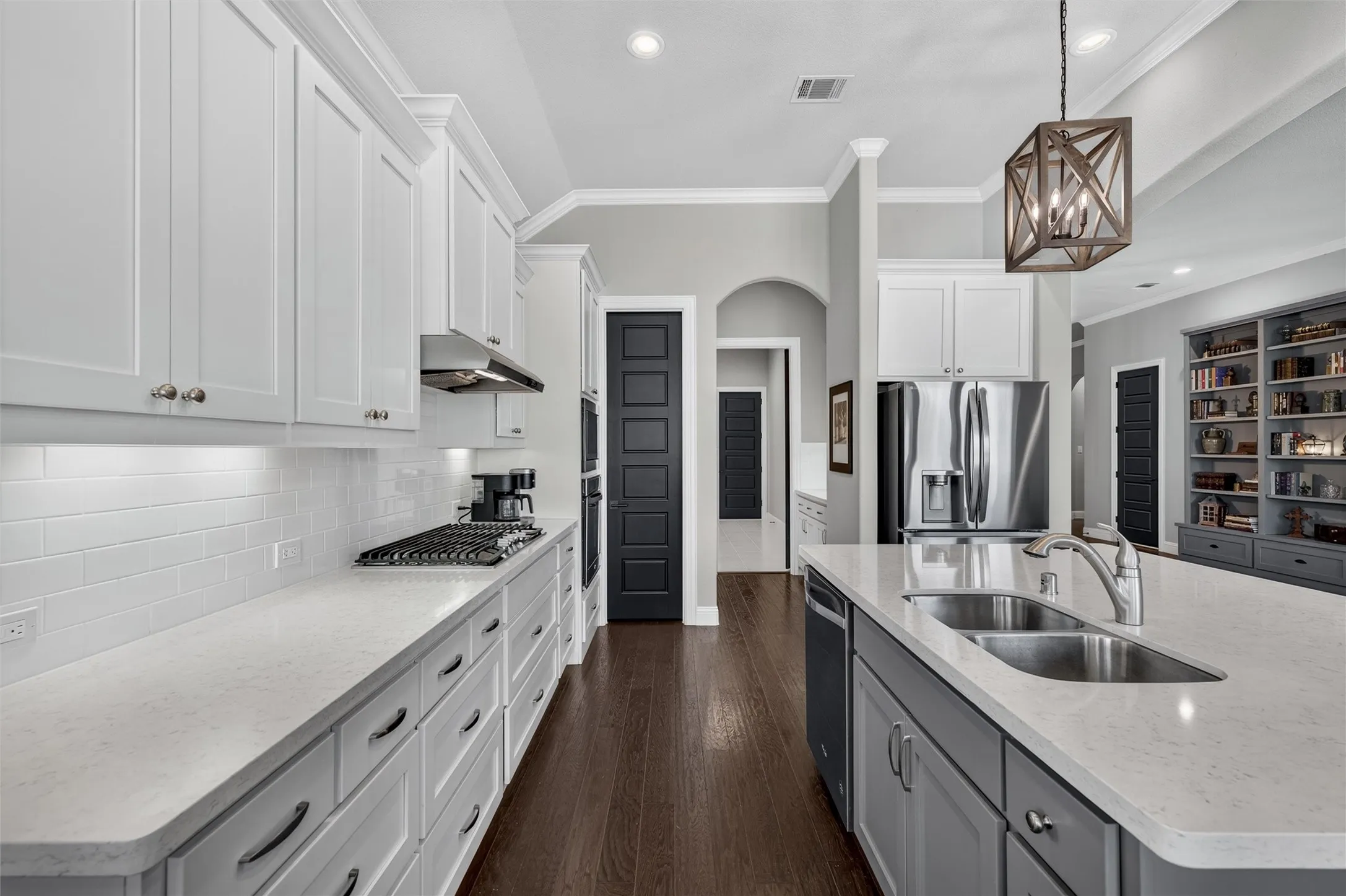 Gourmet kitchen with white upper cabinetry, gray lower cabinetry, light countertops, subway tile backsplash, and dark wood-finish flooring
