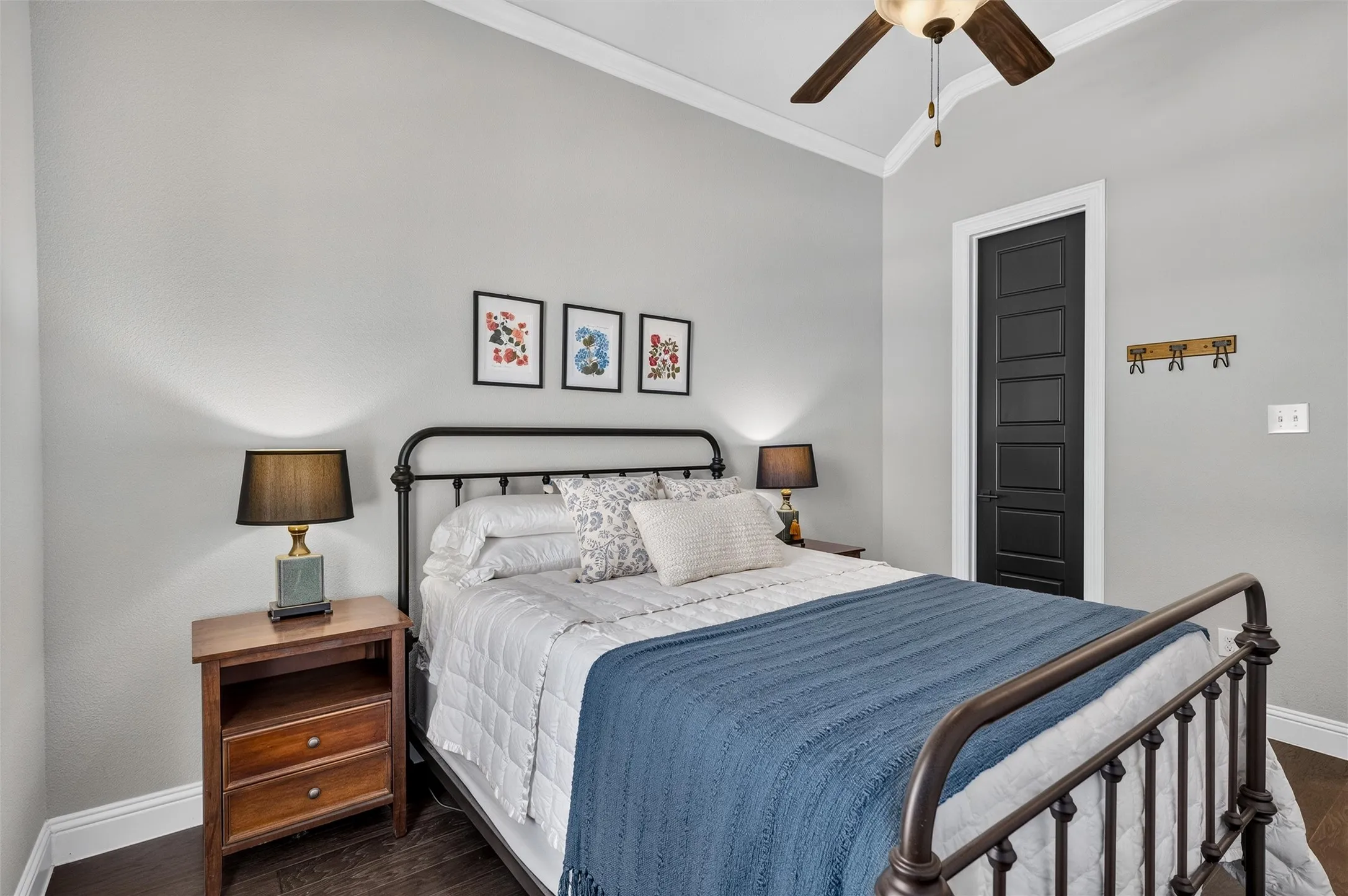 Vaulted ceiling with crown molding, ceiling fan, dark wood-finish flooring, and a five-panel interior door