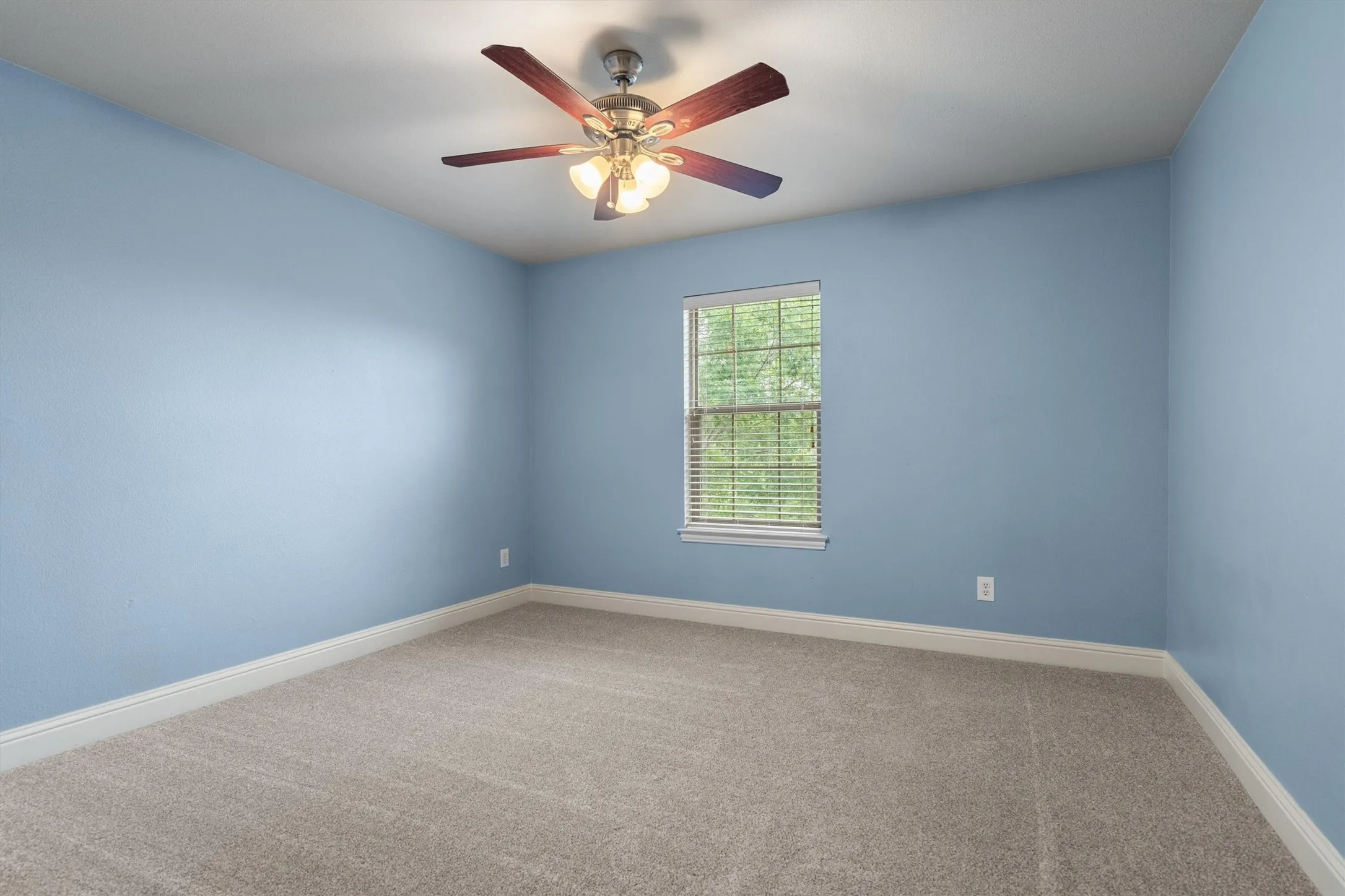 Spacious bedroom with ceiling fan and natural light