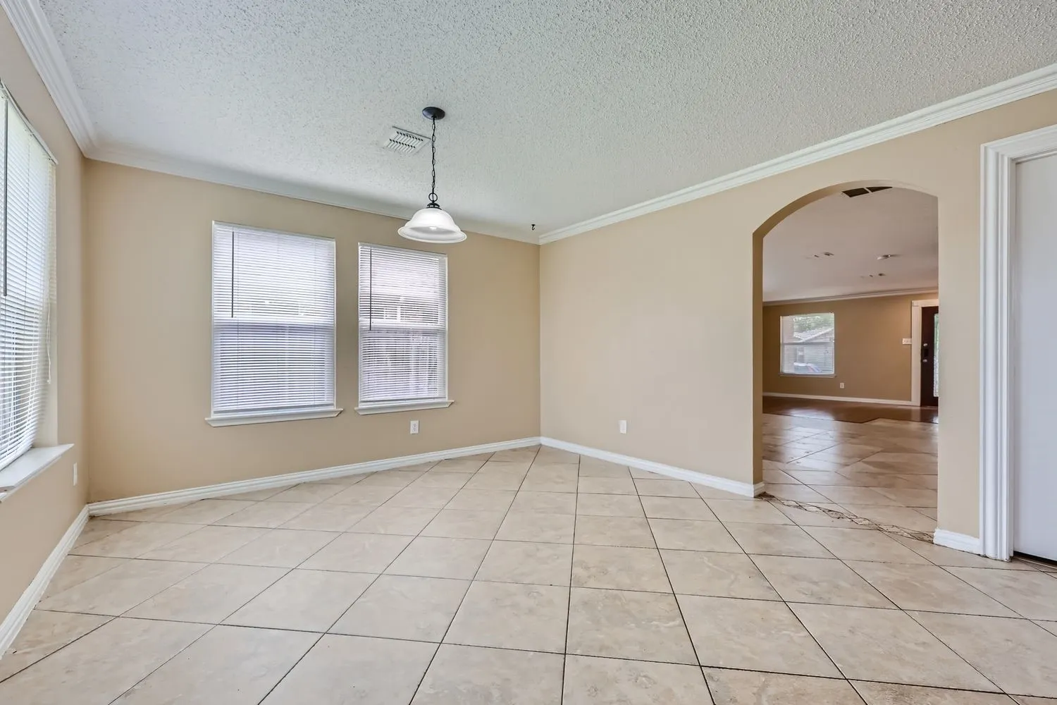 Neutral-toned tile flooring, archway entry, and crown molding accents