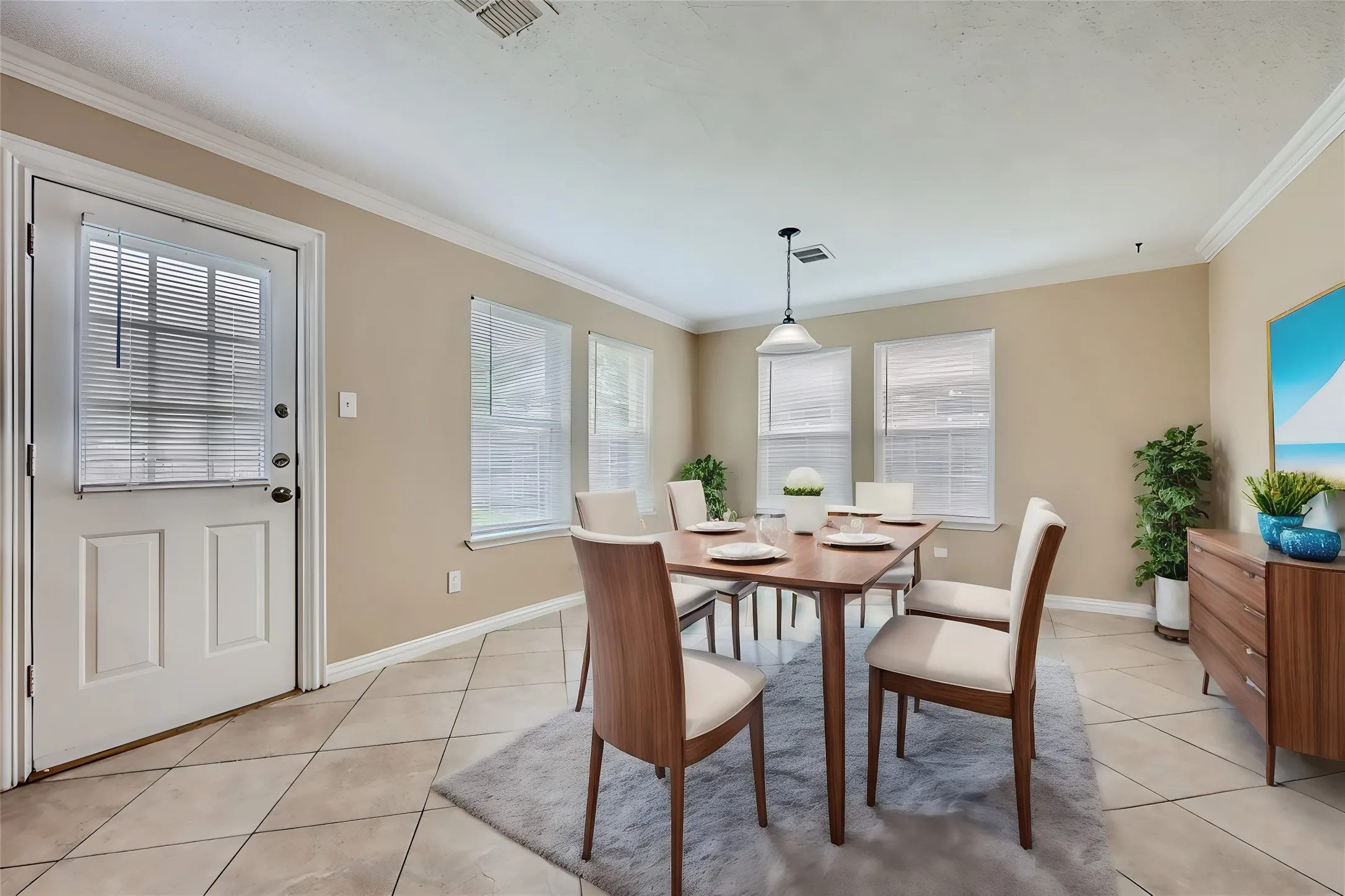 Tile flooring, multiple windows with blinds, white trim, crown molding, and a pendant light fixture