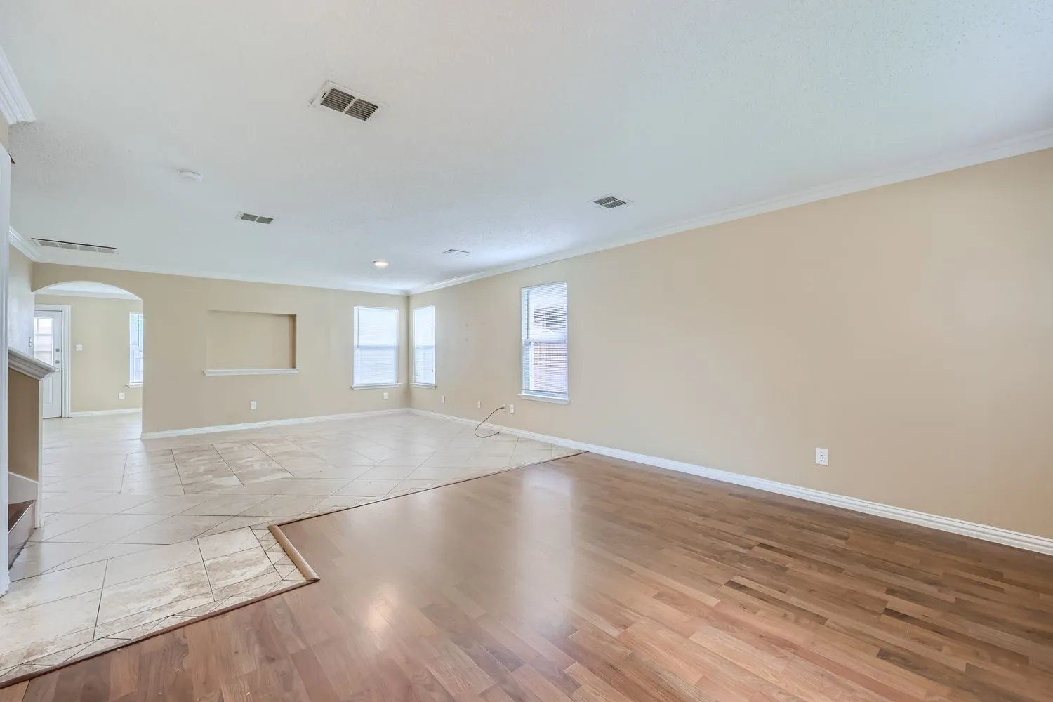 Crown molding, recessed wall niche, multiple windows, wood-finish flooring, and tile flooring