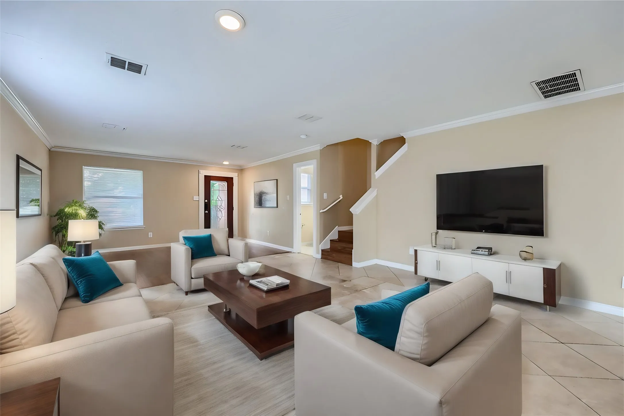 Living area featuring recessed lighting, crown molding, tile flooring, and a hardwood staircase