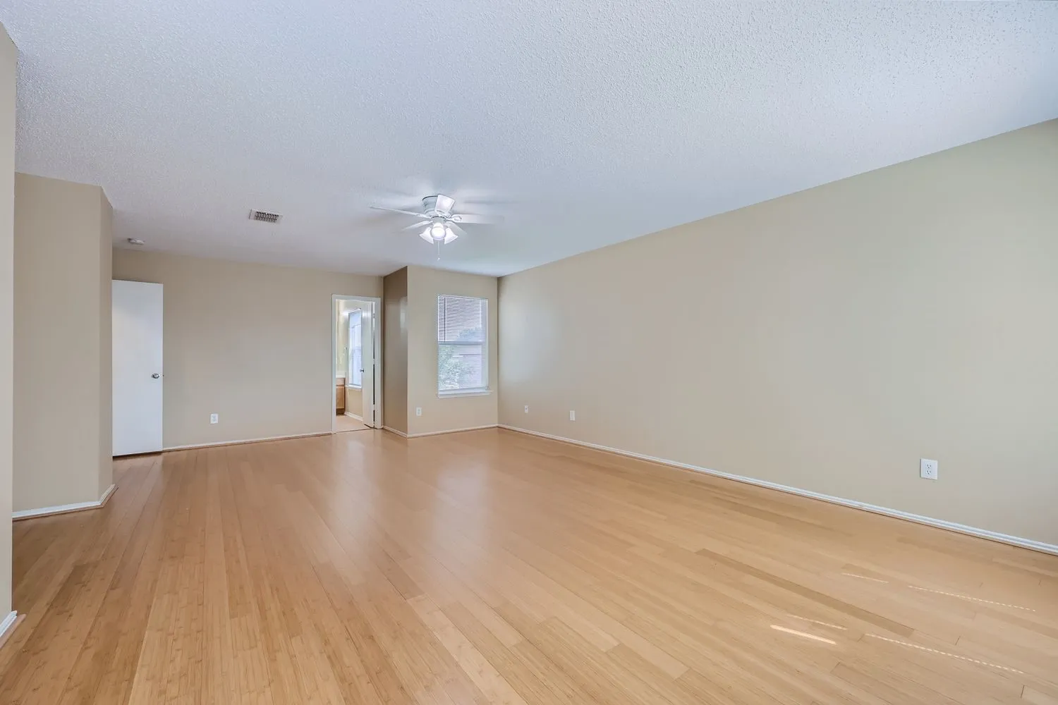 Light wood-finish flooring, neutral wall tones, and overhead lighting with a ceiling fan
