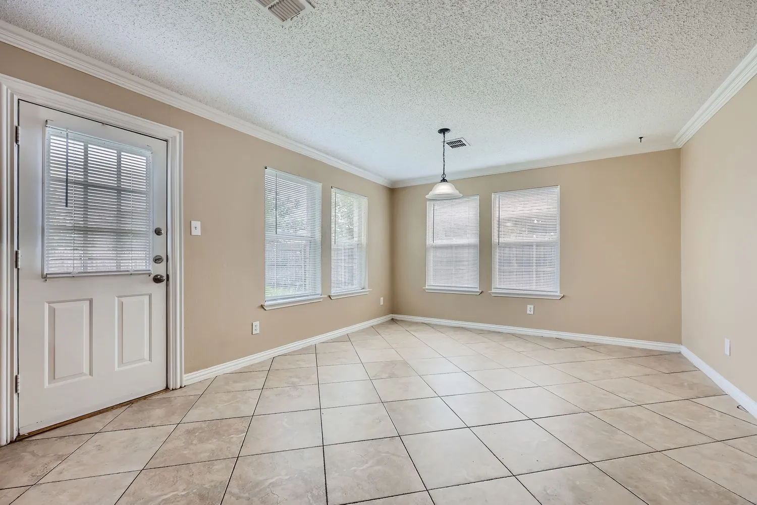 Room featuring ceramic tile flooring, three large windows, a single glass panel exterior door, and a suspended ceiling light fixture