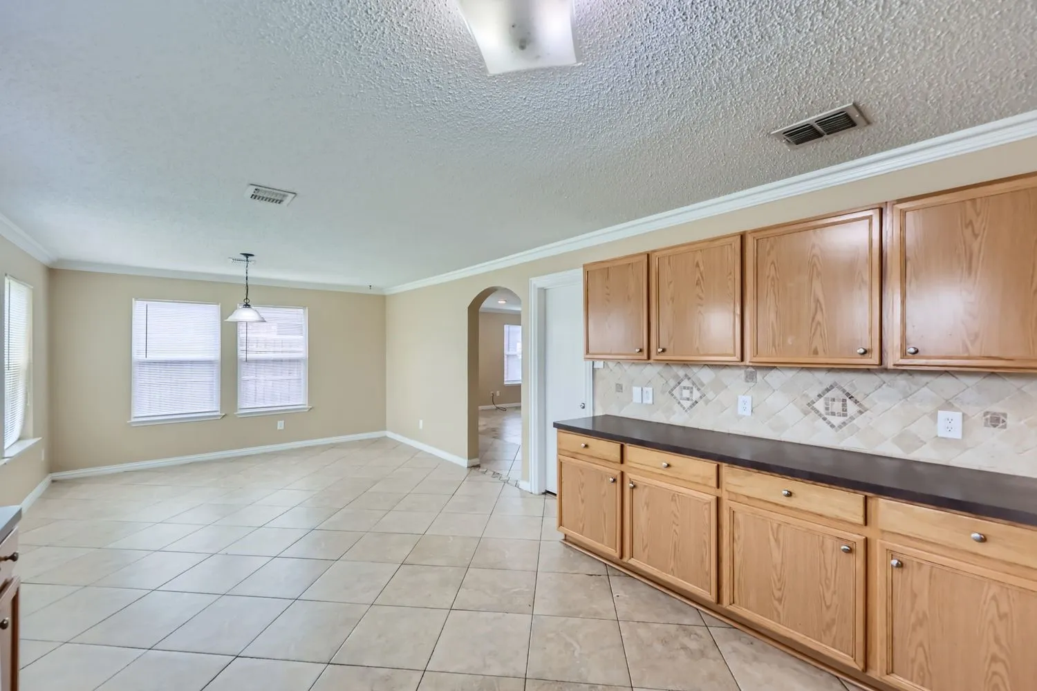 Expansive tile flooring, custom cabinetry with ample storage, decorative tile backsplash, recessed lighting, and crown molding