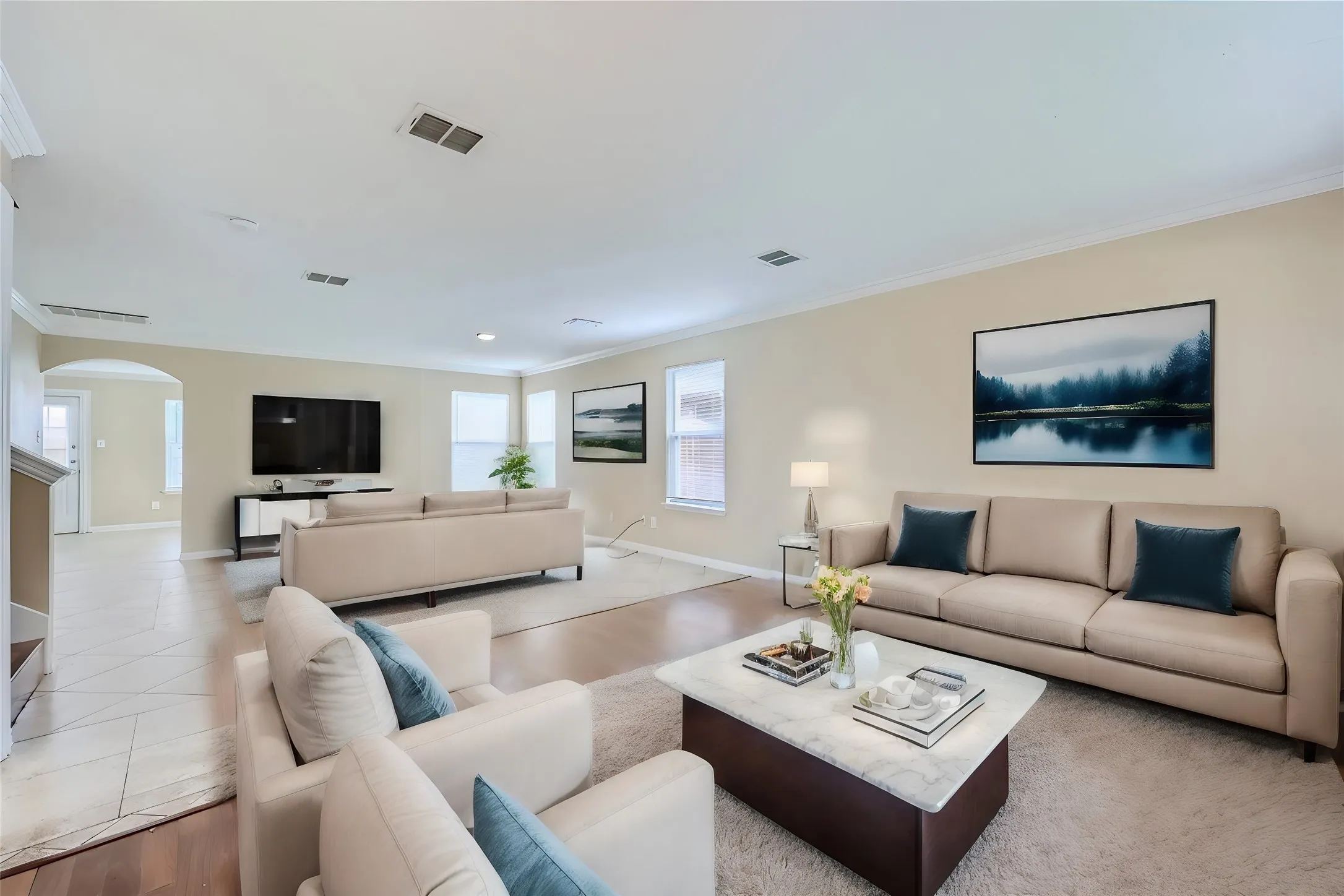 Open-concept living area featuring wood-finish flooring, crown molding, and recessed lighting