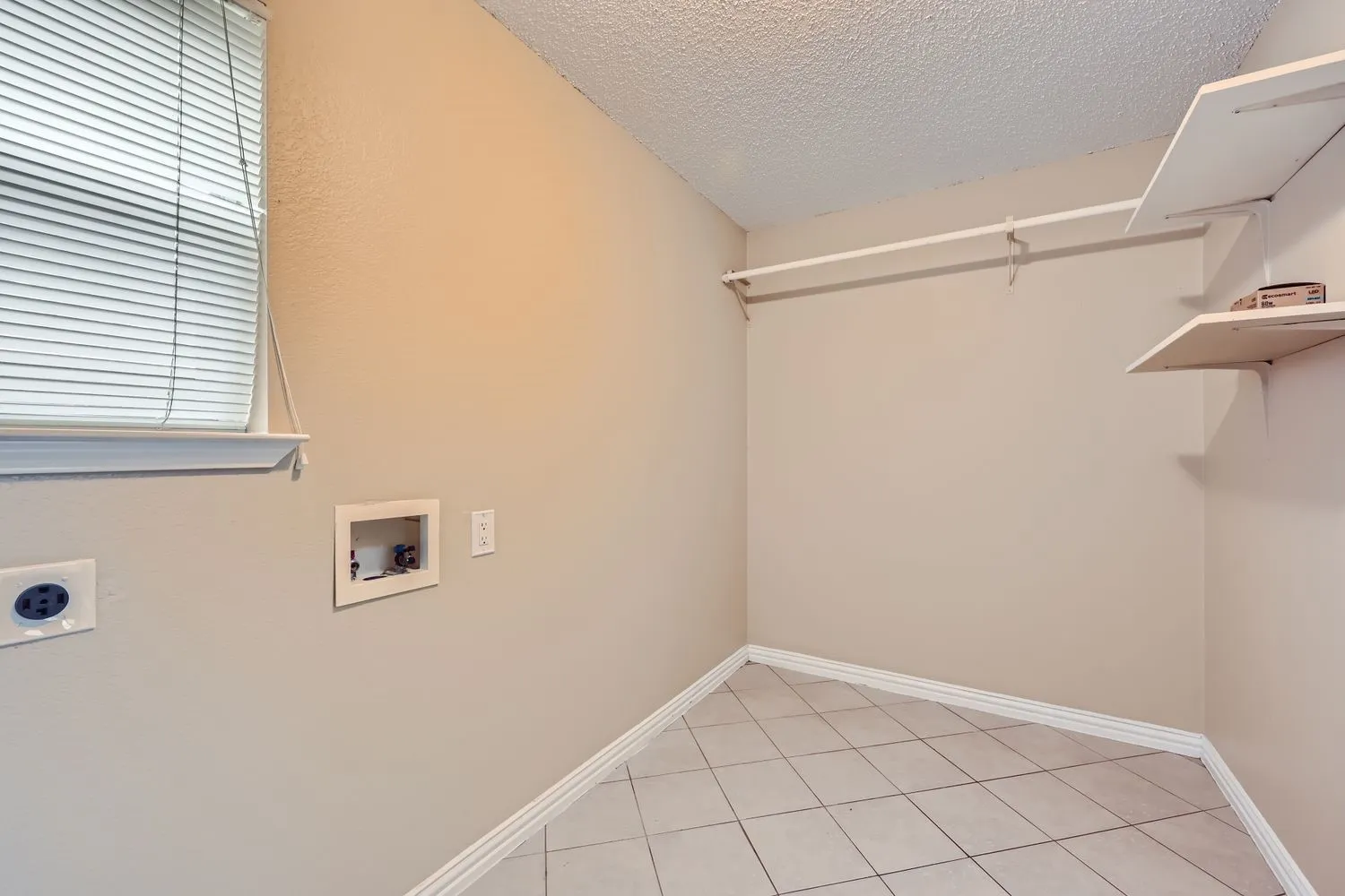 Utility area featuring tile flooring, built-in shelving, a clothes hanging rod, and a window with blinds