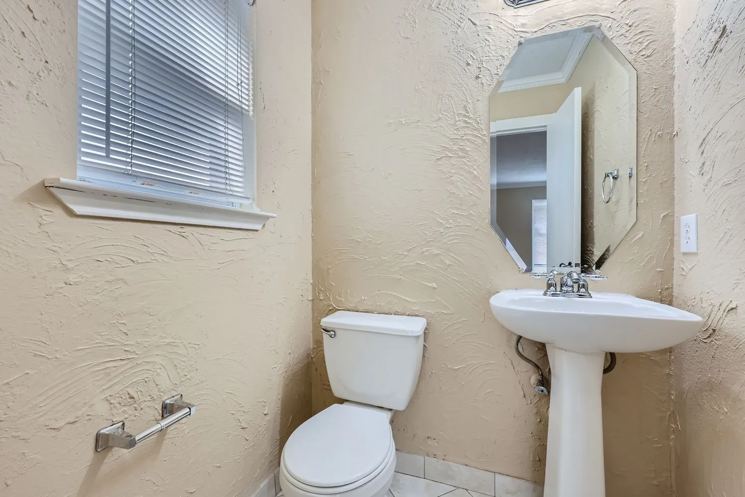 Pedestal sink, wall-mounted mirror, and window with blinds