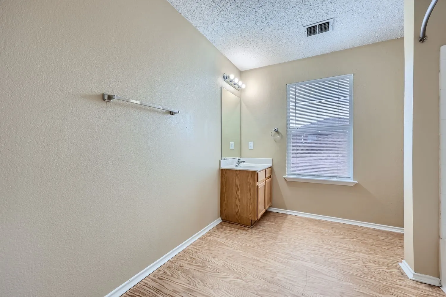 Vanity with wood-finish cabinetry, integrated sink, and wall-mounted mirror