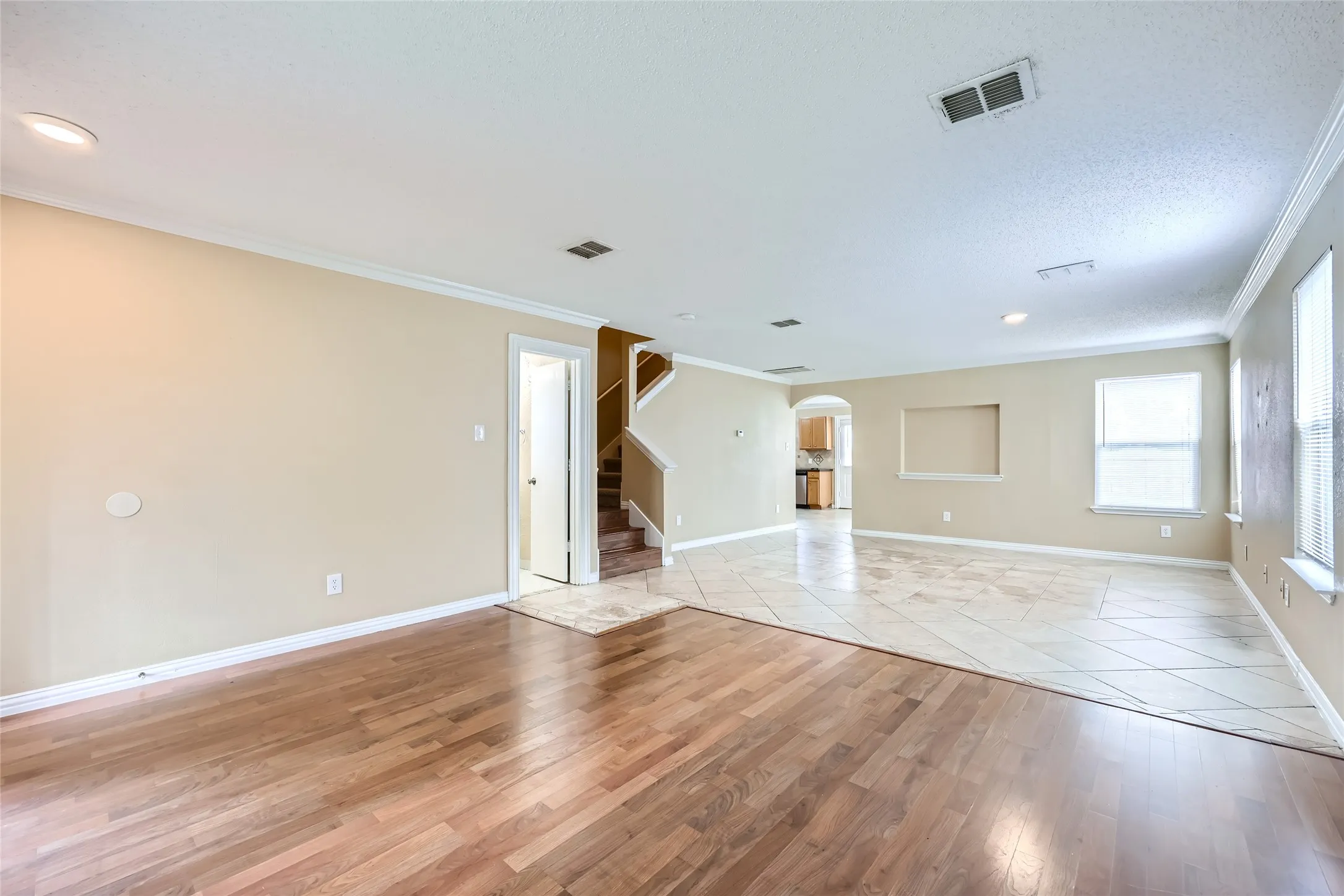 Expansive main living area featuring wood-finish flooring and tile flooring, recessed lighting, and crown molding