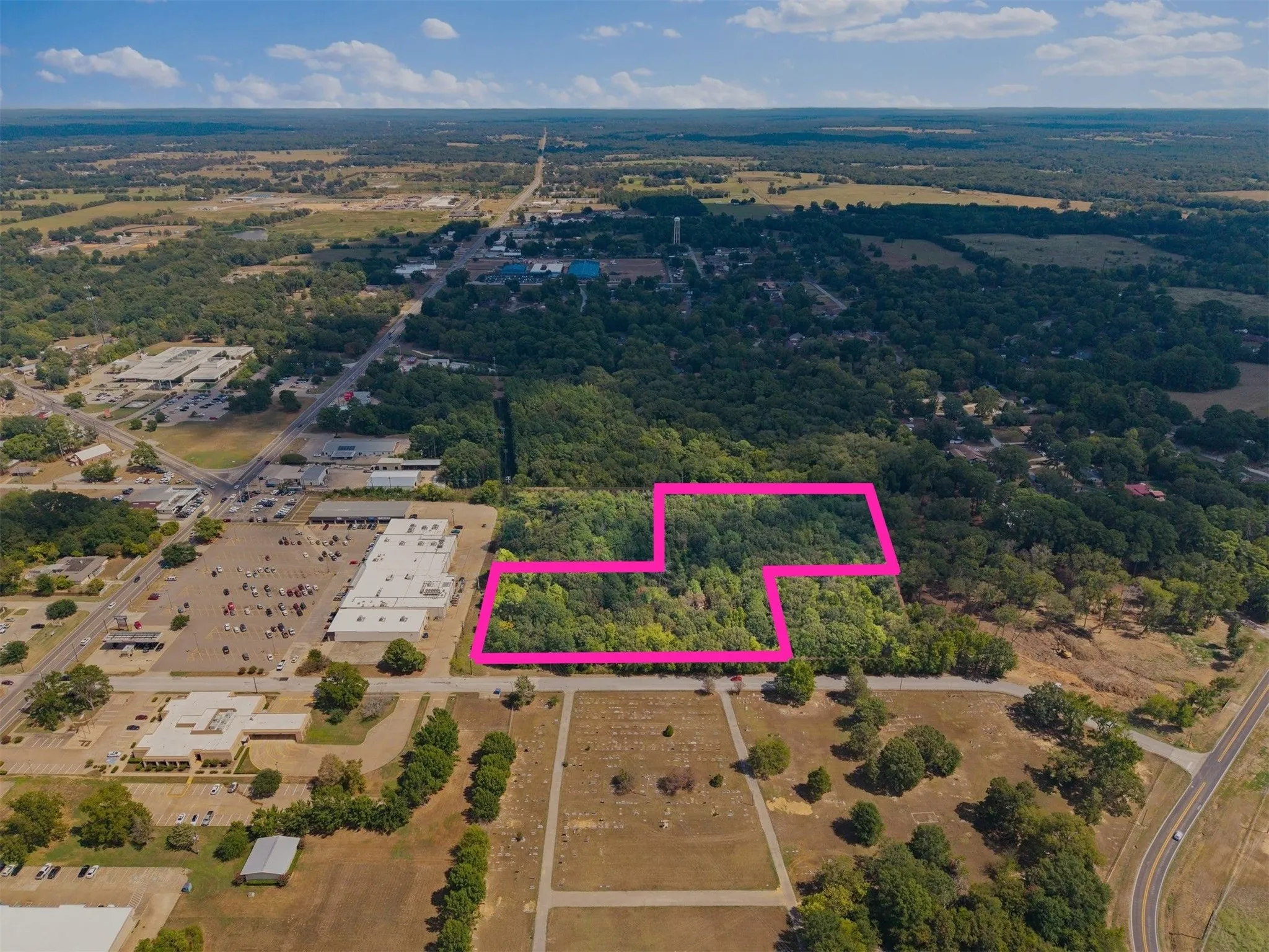 Expansive land parcel with surrounding wooded areas and road access