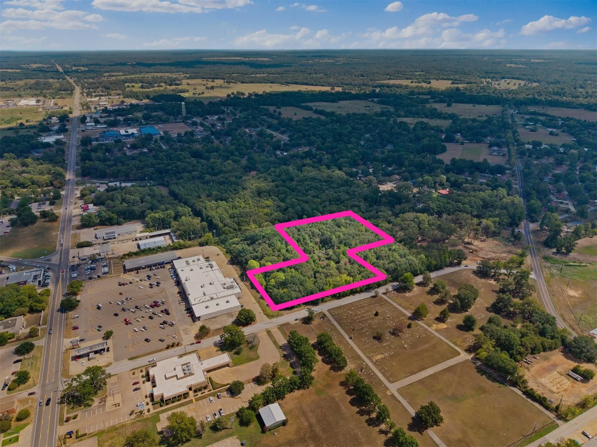 Expansive wooded land parcel, bordered by a commercial area and roadways