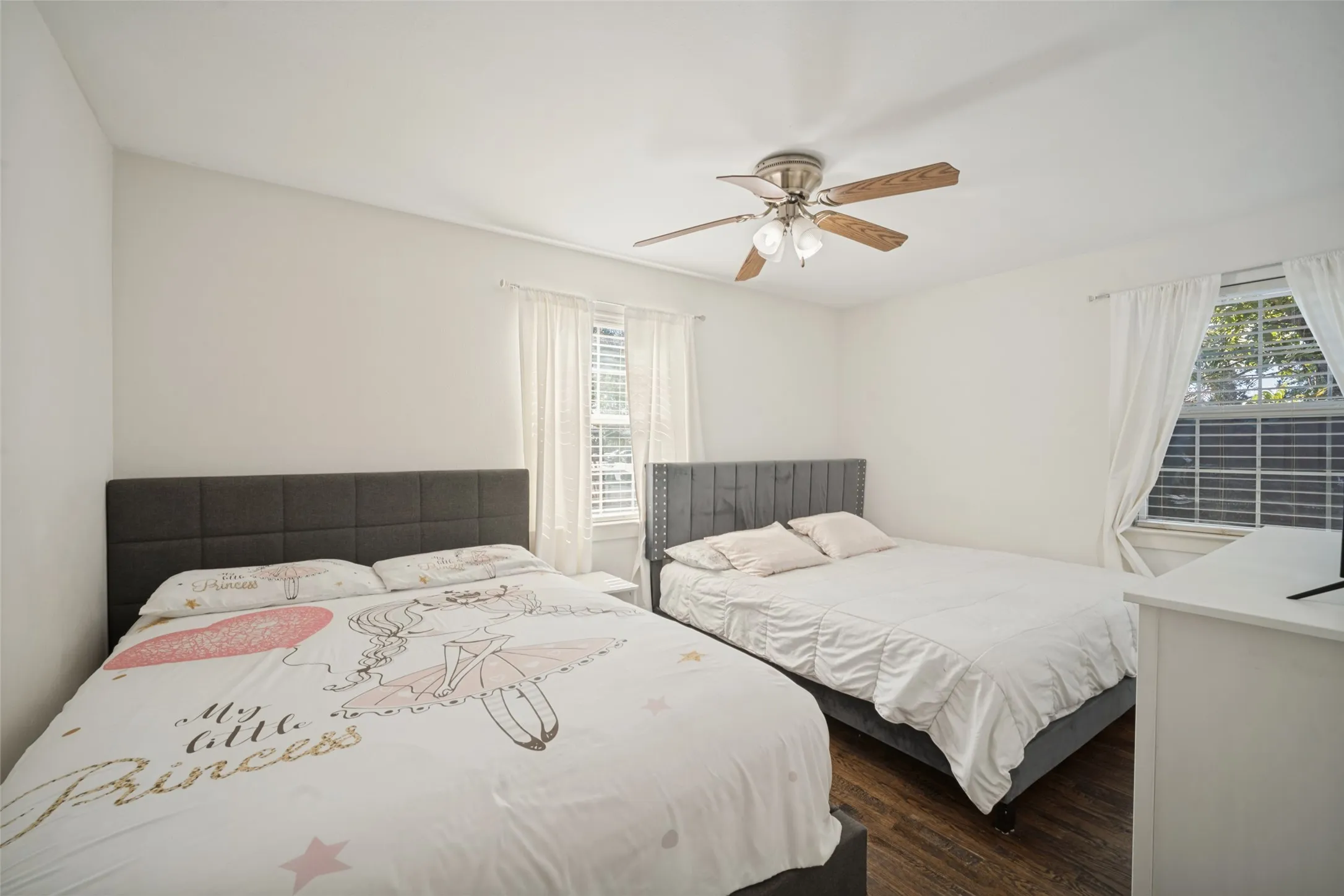 Hardwood-style flooring, window with blinds and drapes, and a ceiling fan with light fixture