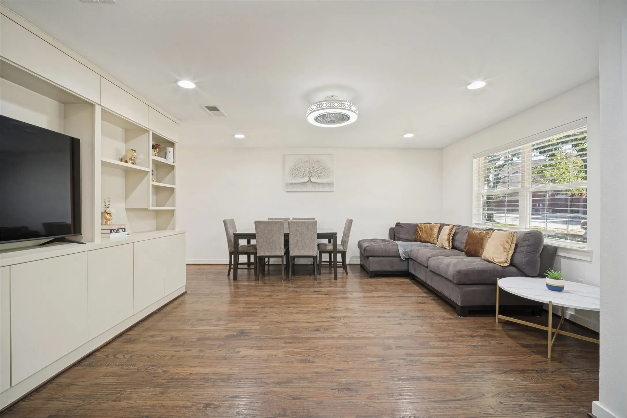 Open-concept living space with wood-finish flooring, recessed lighting, and built-in cabinetry