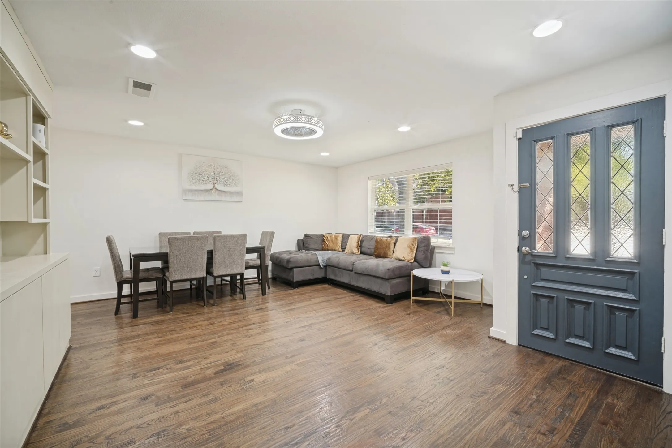 Hardwood-finish flooring throughout, recessed lighting, built-in shelving, and a decorative front entry door with glass panels