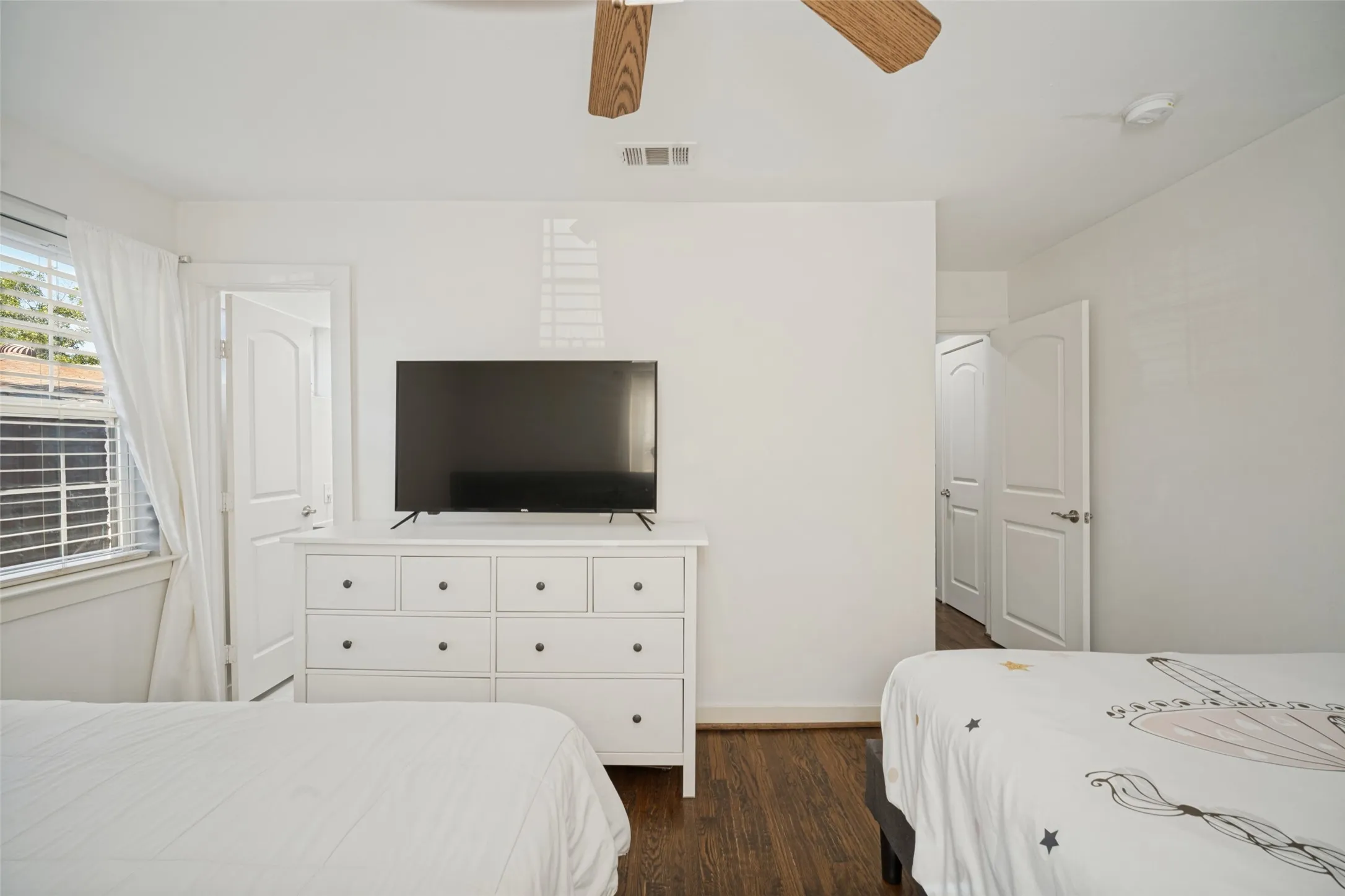 Wood-finish flooring with white trim, white walls, and a ceiling fan