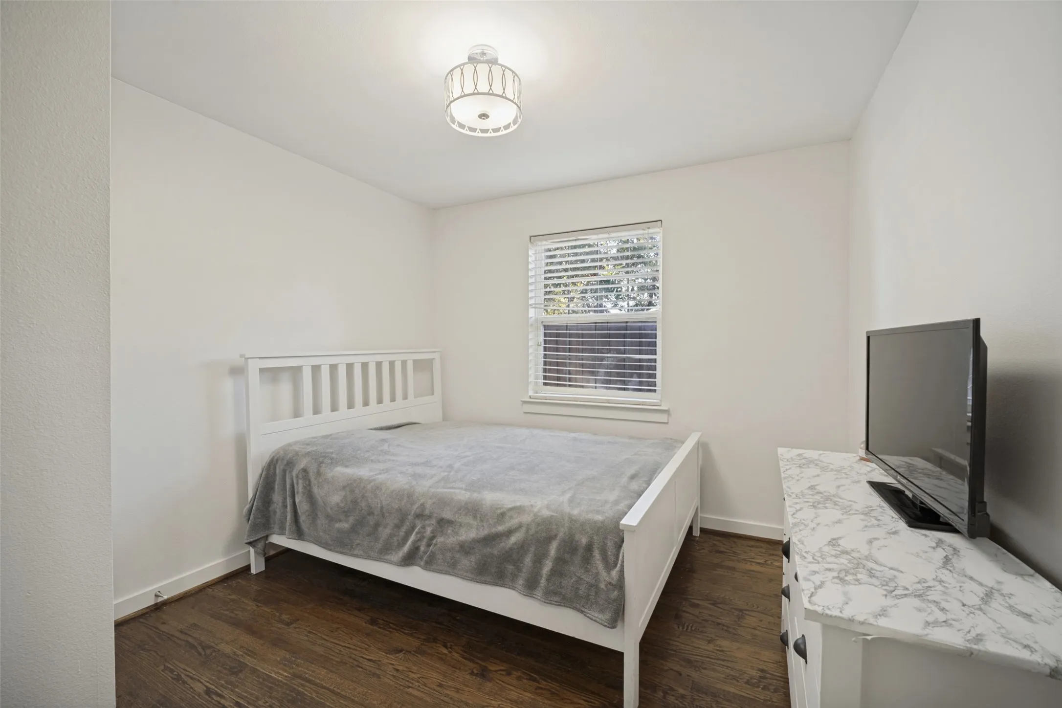 Recessed window with blinds, wood-finish flooring, white walls, and a semi-flush mount ceiling light