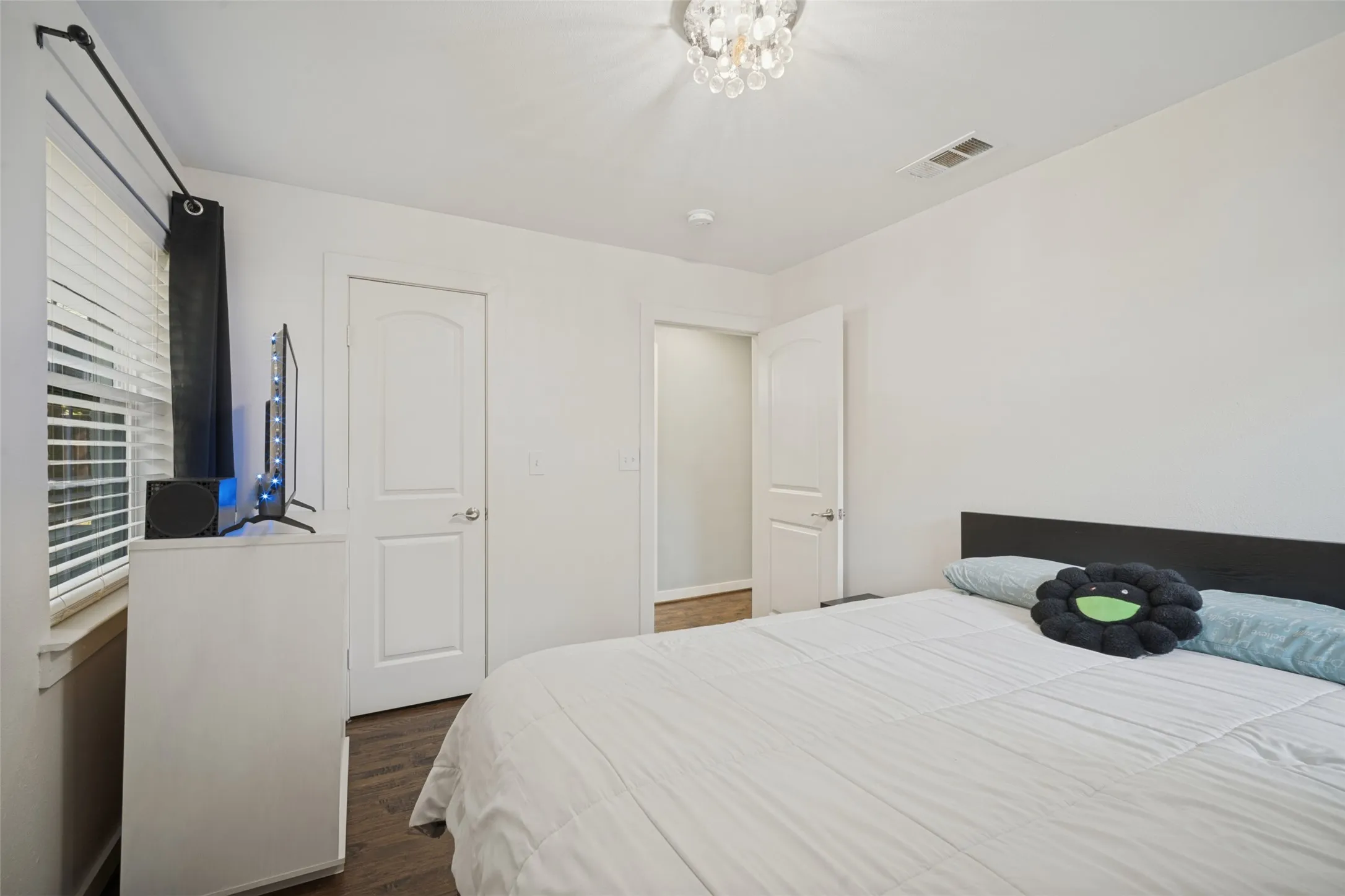Recessed lighting, wood-finish flooring, white walls, and a crystal chandelier
