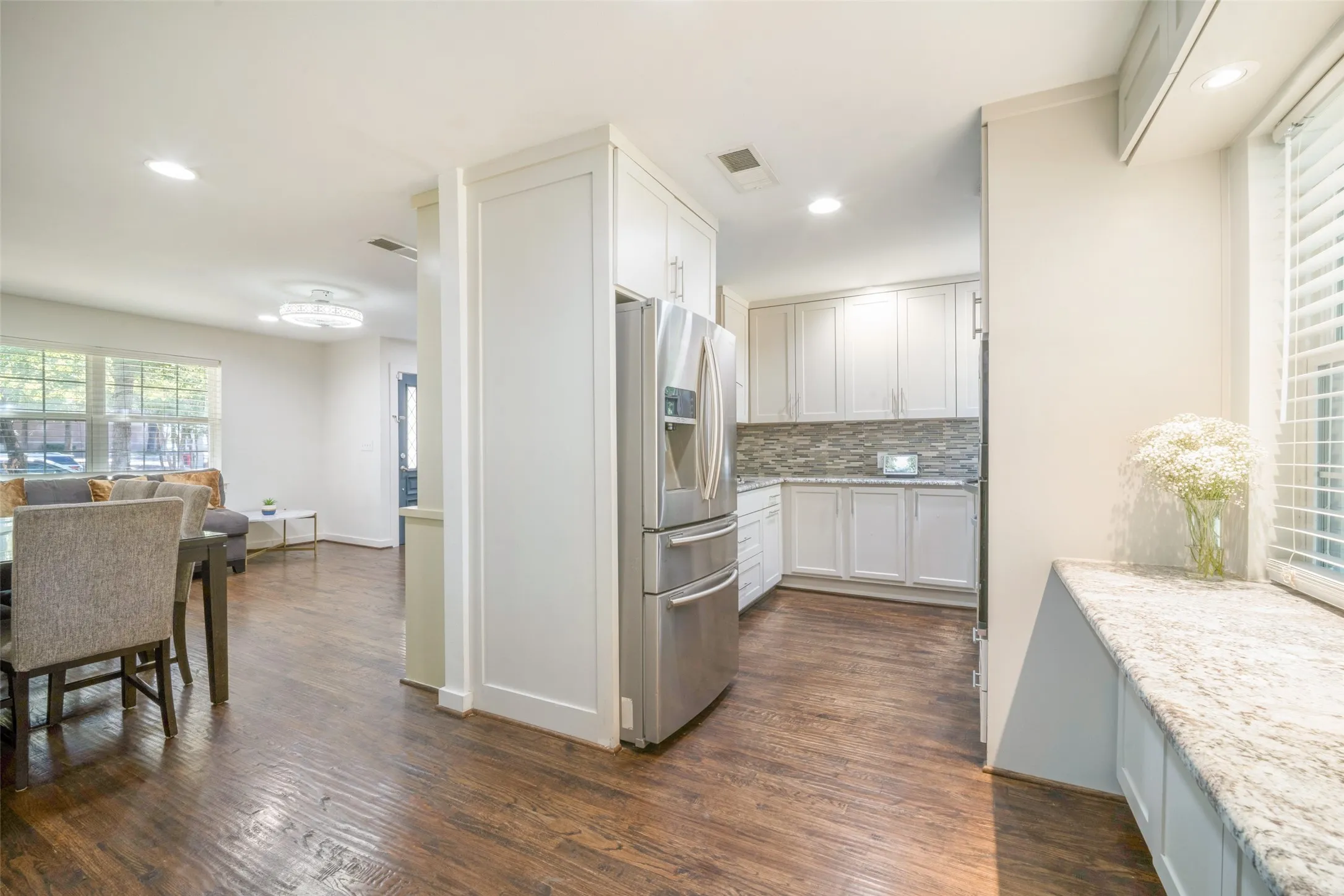 Kitchen featuring stainless steel appliances, white cabinetry, tile backsplash, and recessed lighting