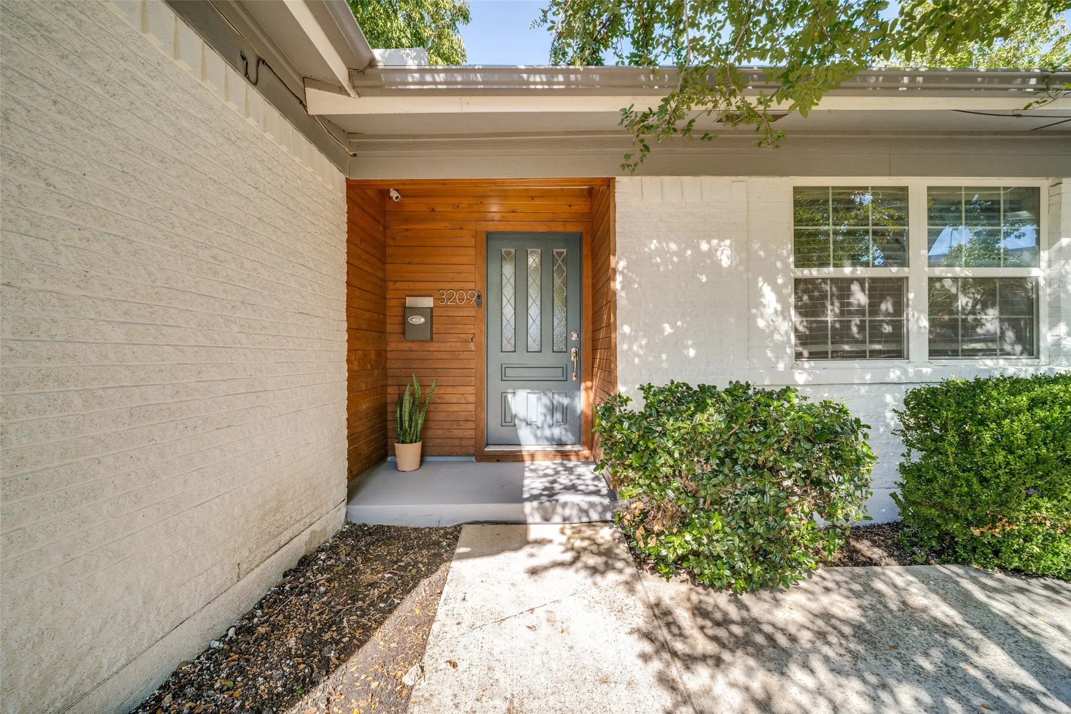 White brick exterior with a wood-paneled entry