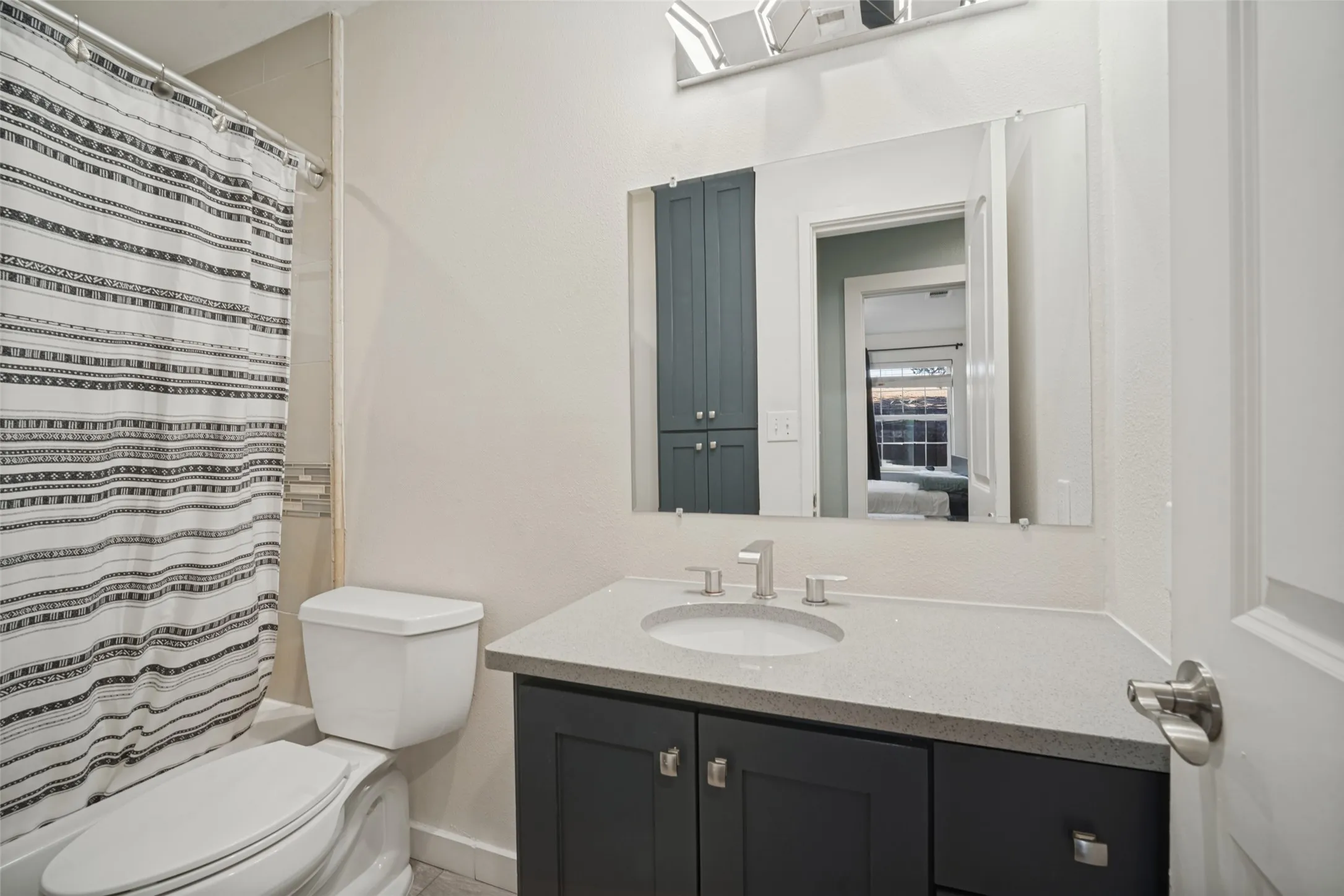 Vanity with a light-toned countertop, under-mount sink, and dark cabinetry