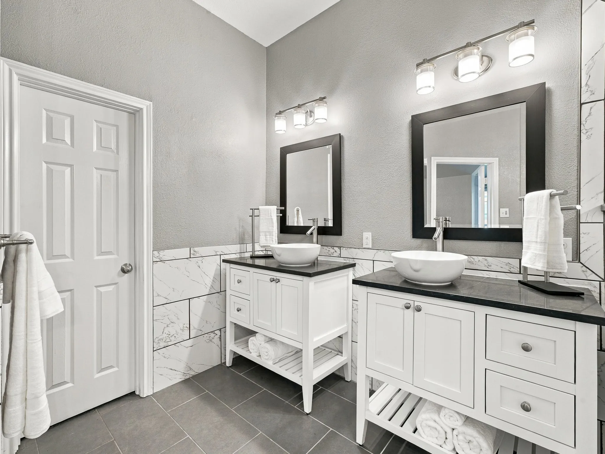 Dual vanity setup with white shaker cabinetry, dark countertops, and vessel sinks