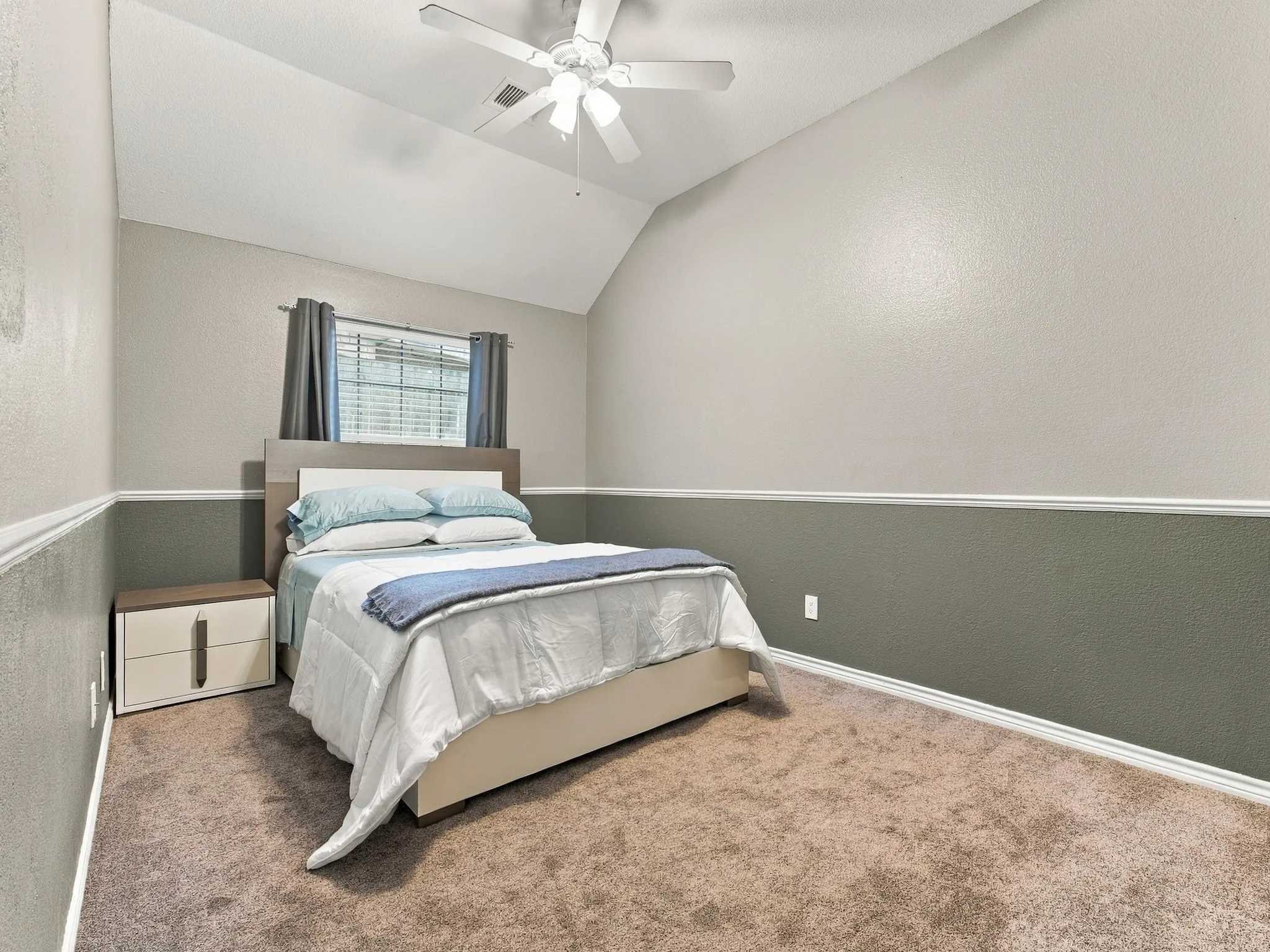 Vaulted ceiling with a ceiling fan, carpeted flooring, and a window with blinds